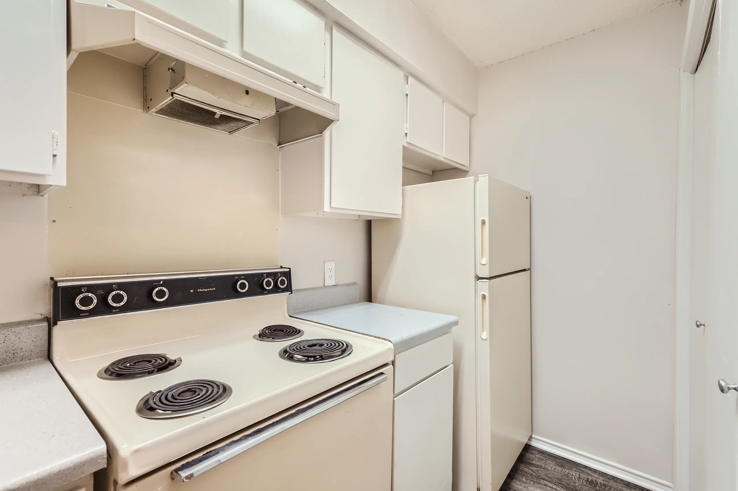 Apartment kitchen with white cabinetry, electric range, and side-by-side refrigerator