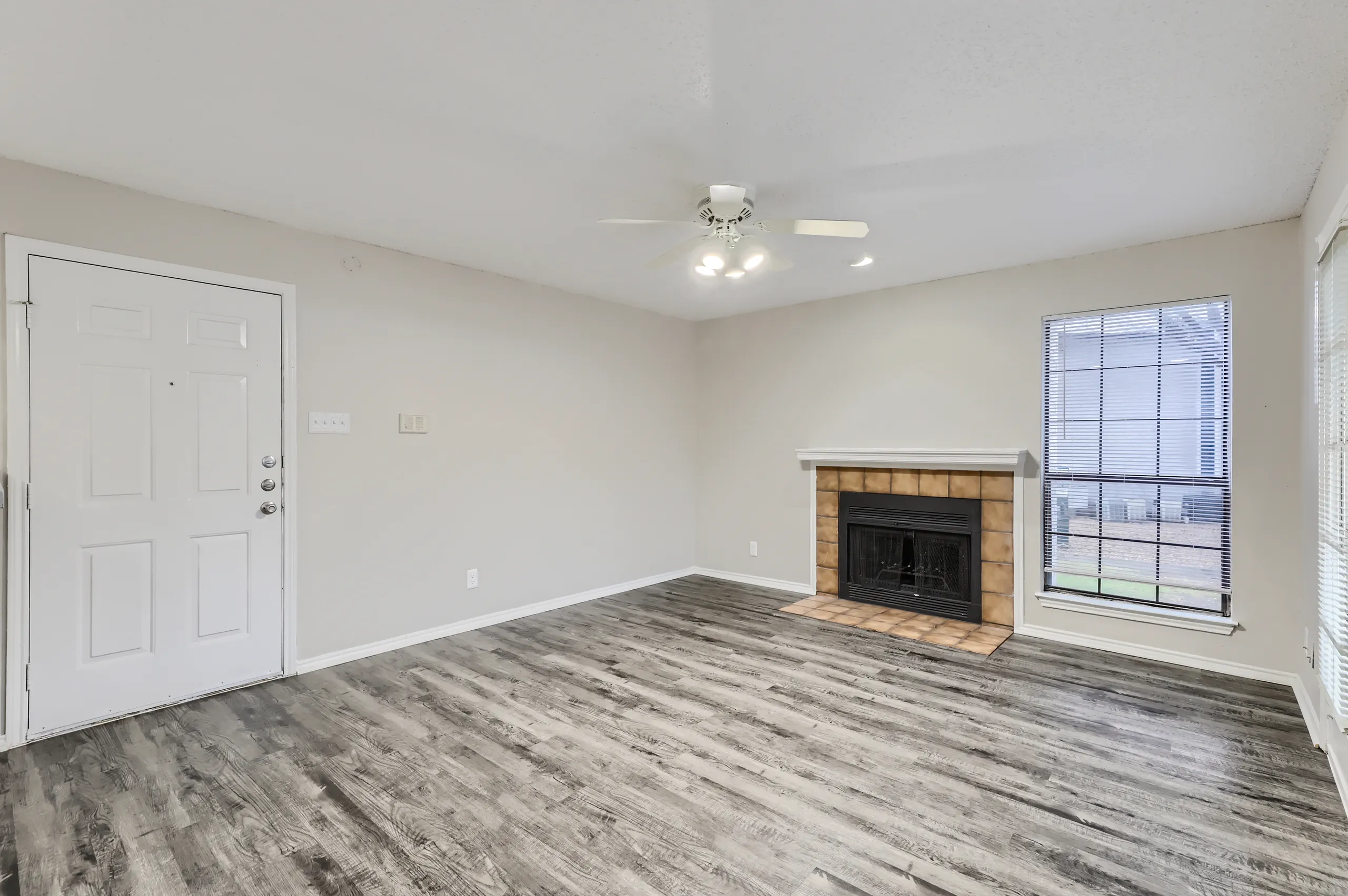 Living room with tiled wood-burning fireplace and wood-look flooring