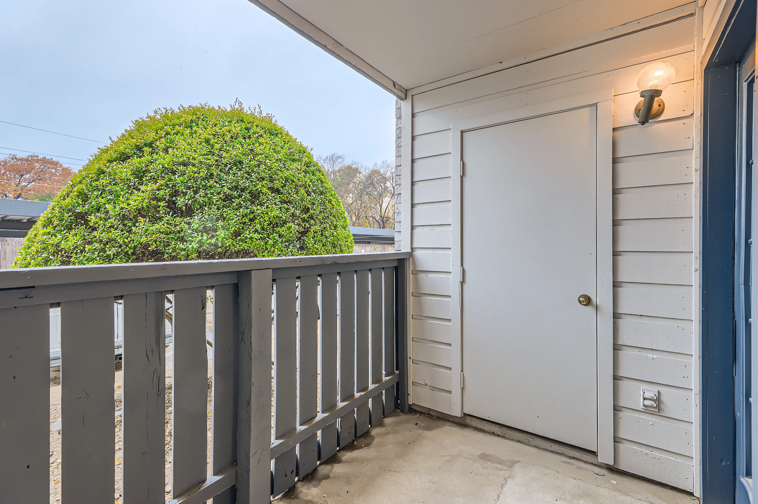 Private apartment balcony with storage closet and view of greenery
