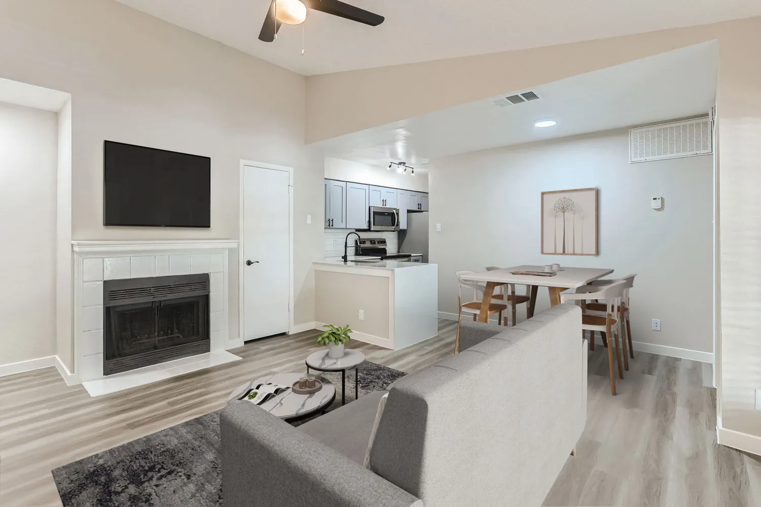 Living room with tiled fireplace, mounted TV, and open kitchen and dining view
