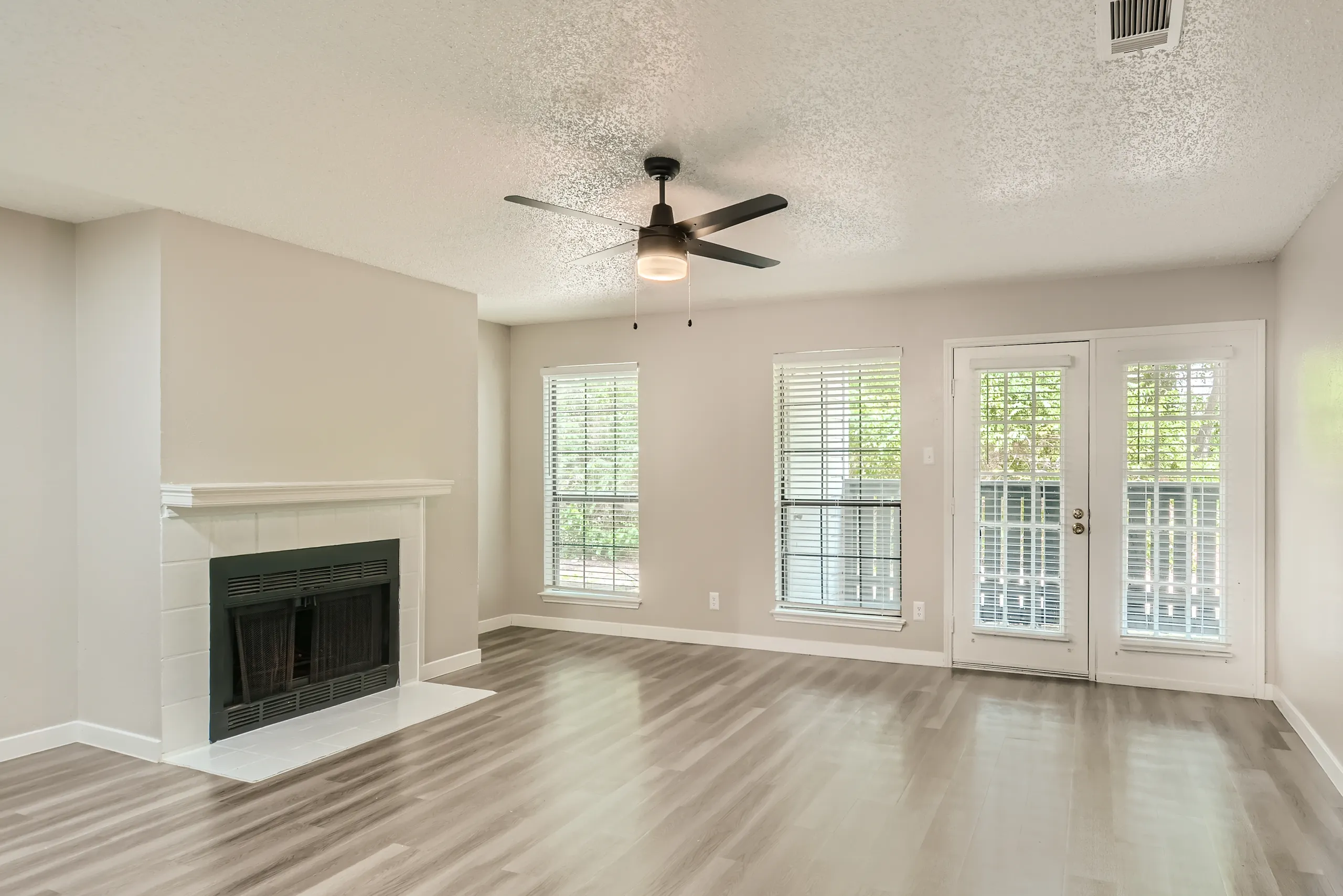 Living room with tiled fireplace and French door patio access