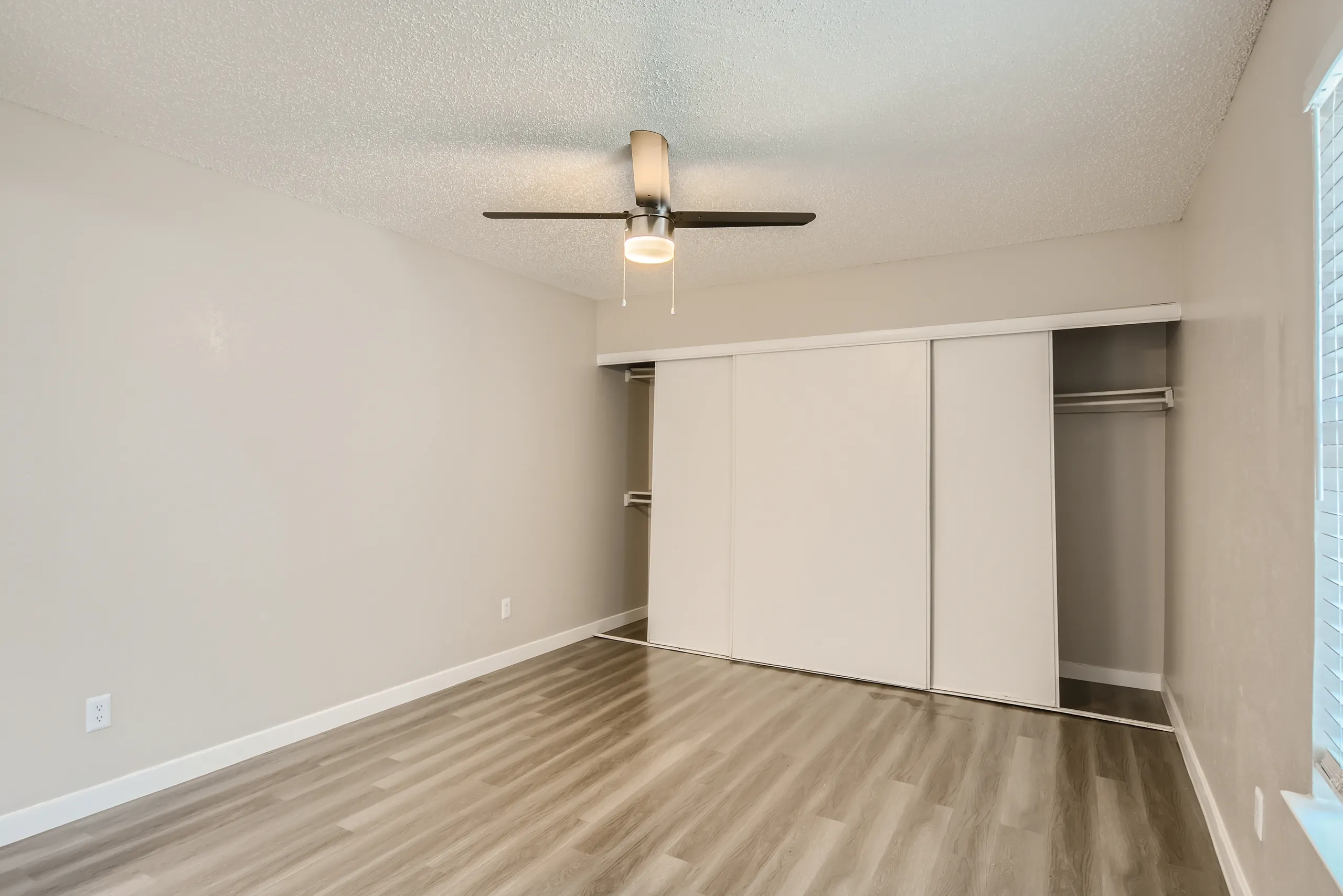 Primary bedroom with sliding closet doors and wood-look flooring
