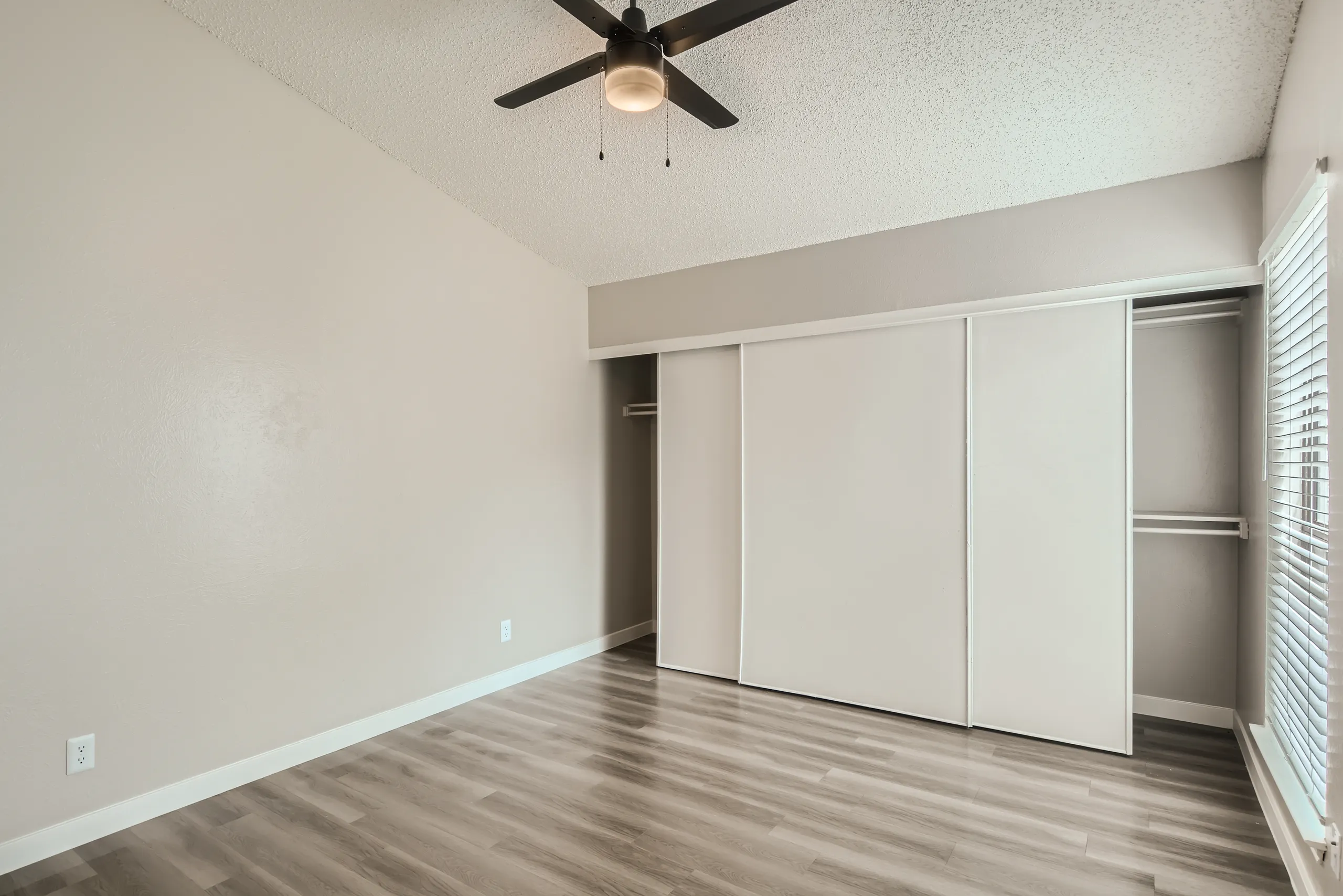 Primary bedroom with sliding closet doors and wood-look flooring