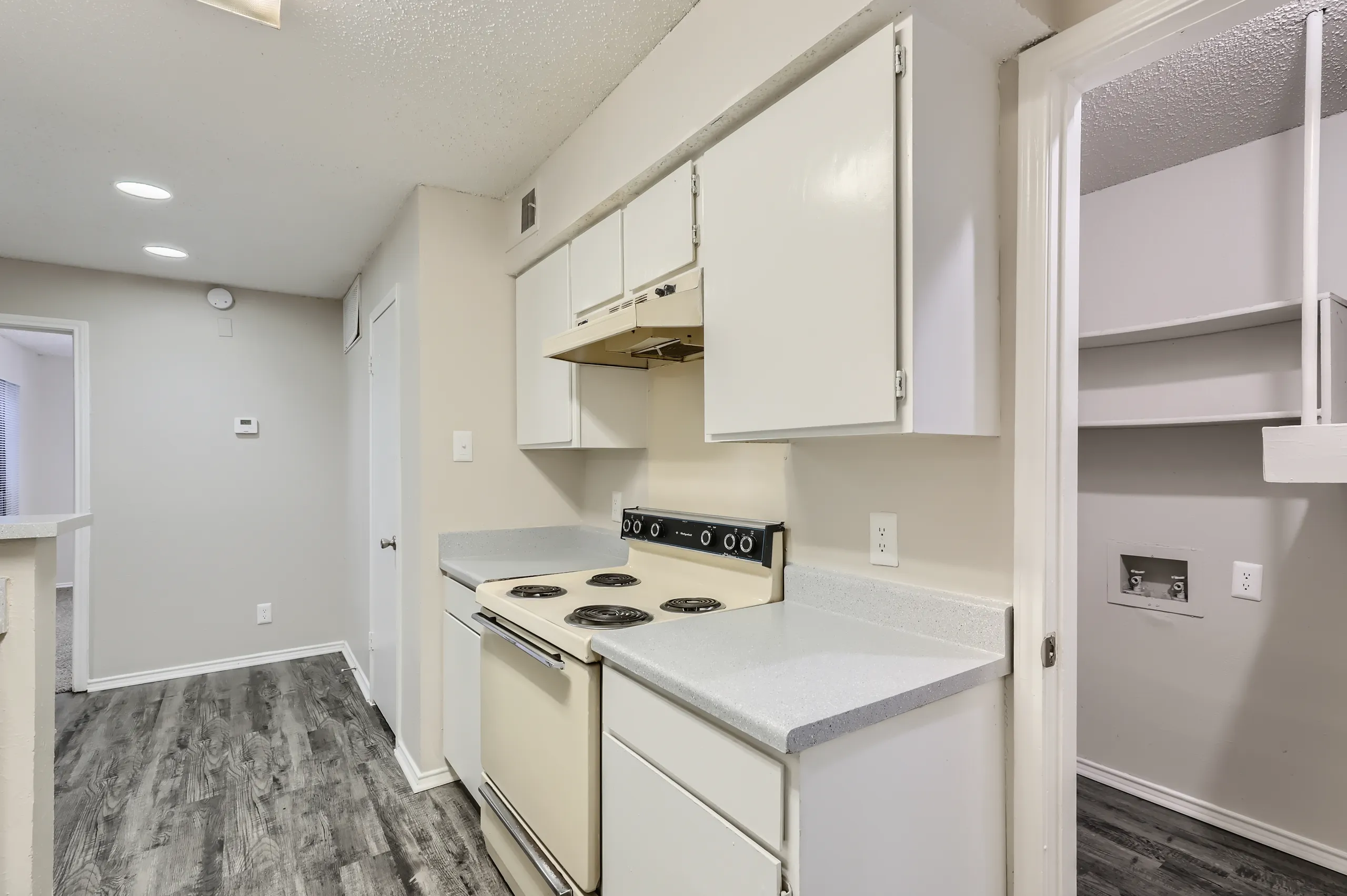 Apartment kitchen with white cabinetry and electric range