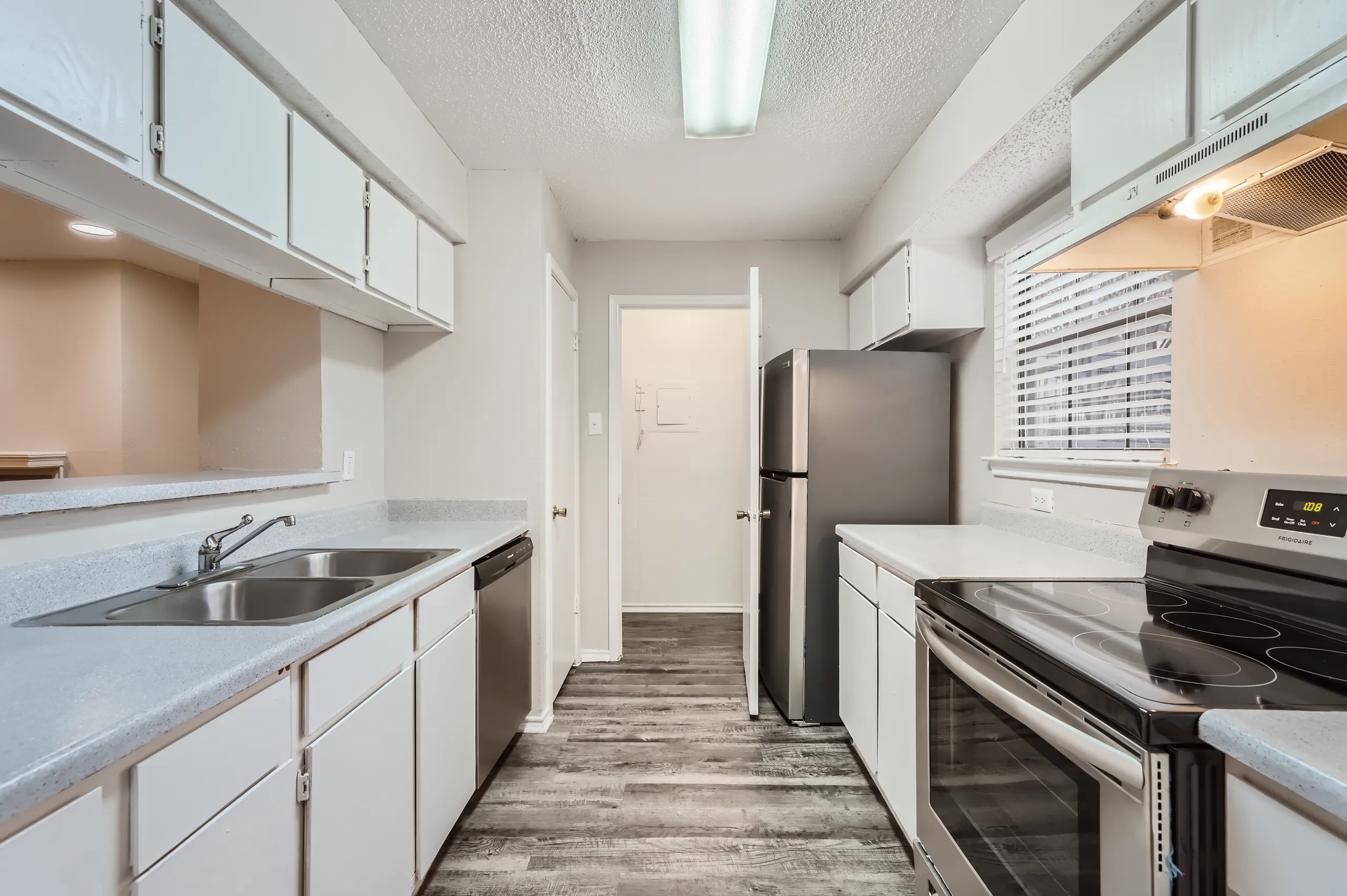 Galley kitchen with white cabinetry and stainless steel appliances