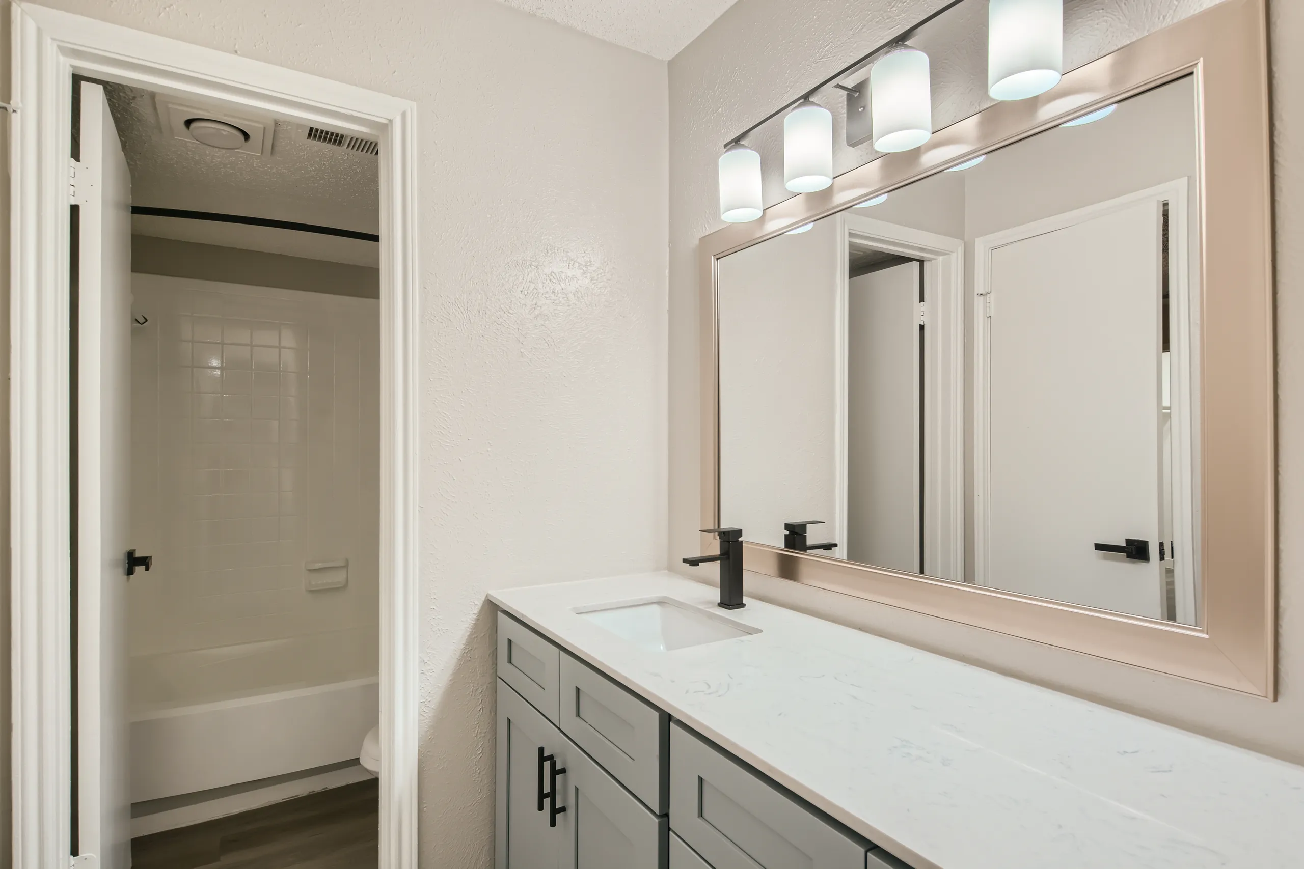 Bathroom with gray vanity and view into tub-shower combo