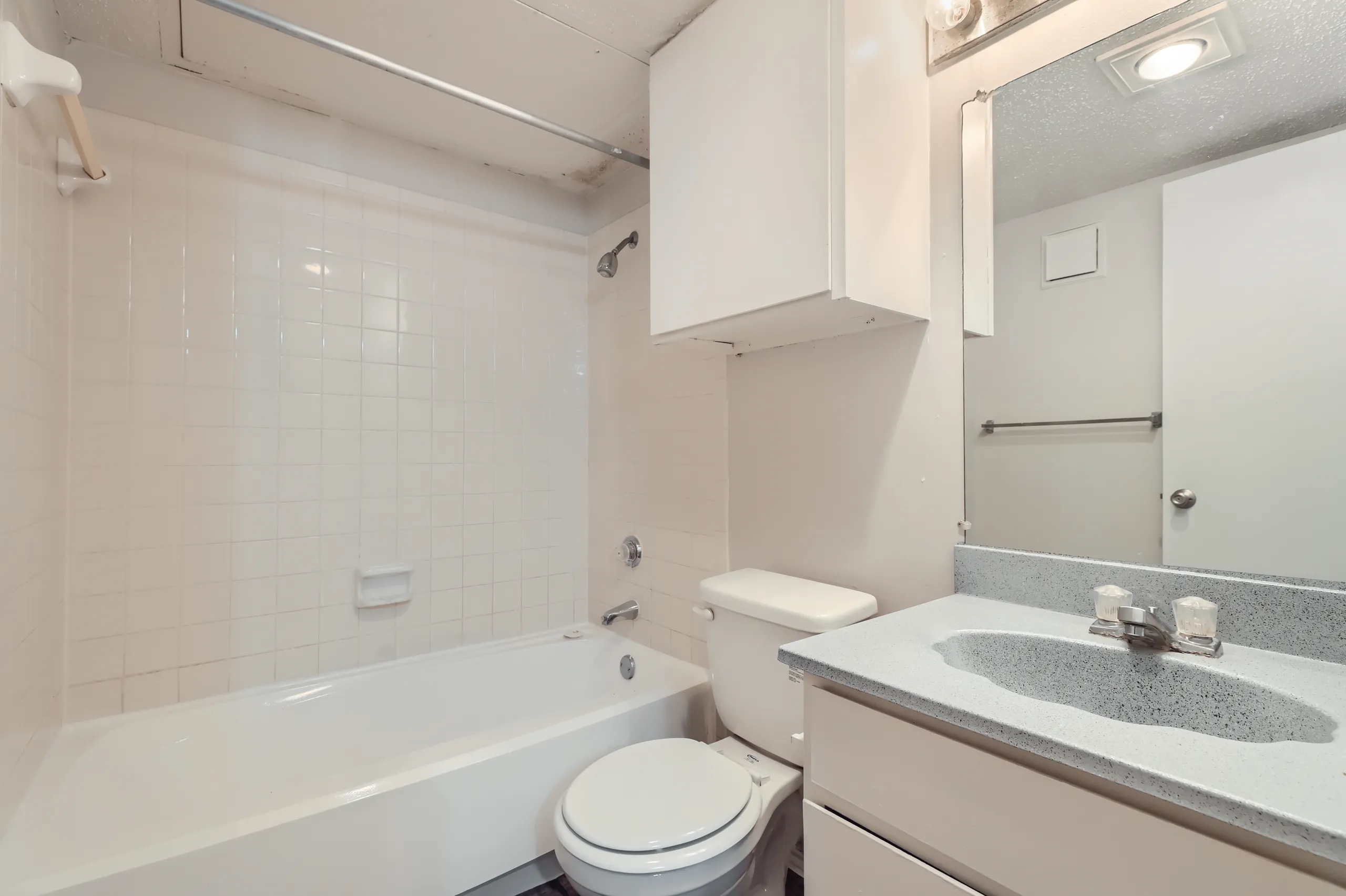 Apartment bathroom with tub-shower combo and single-sink vanity