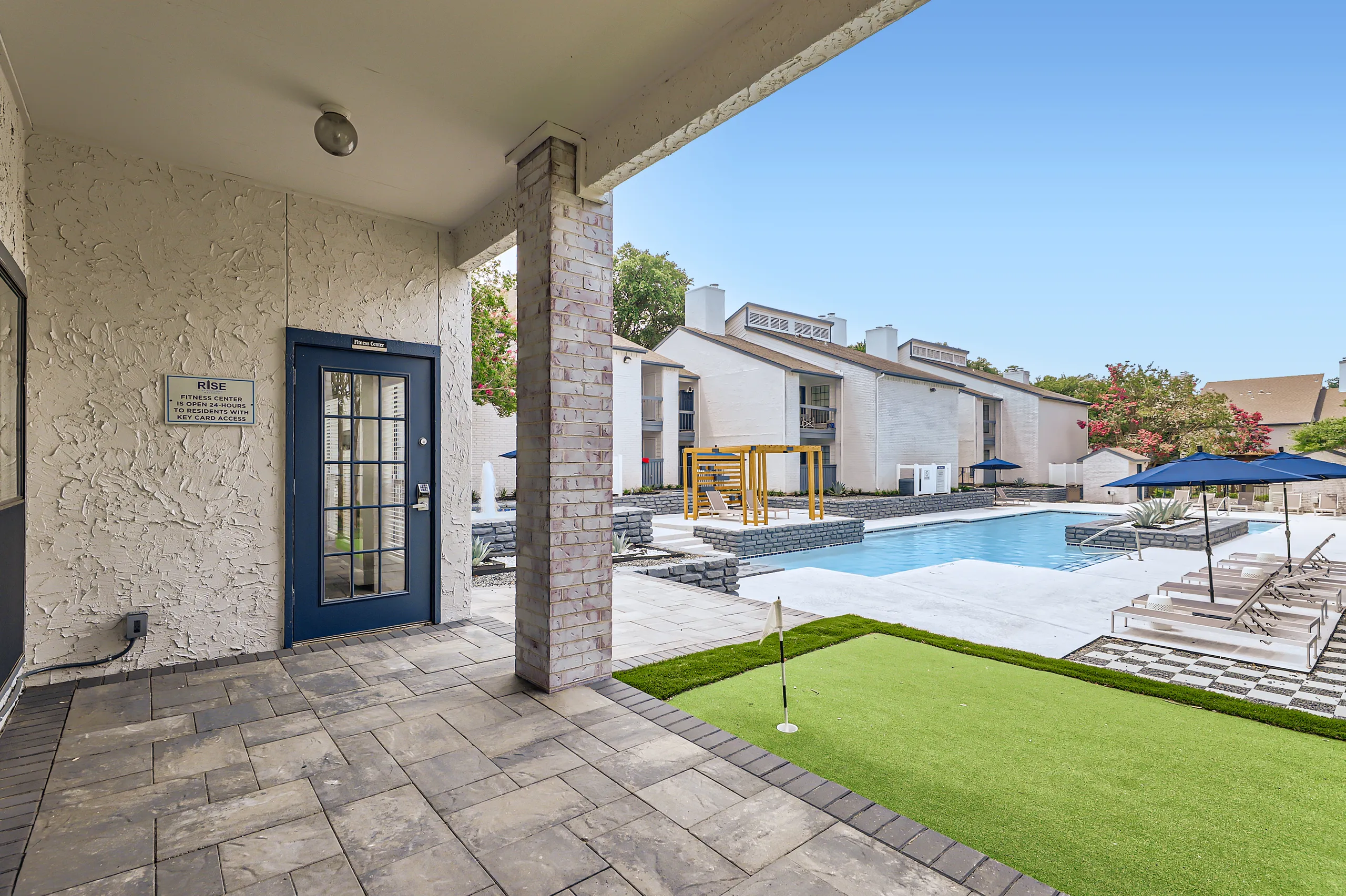 Covered patio outside fitness center overlooking pool and putting green
