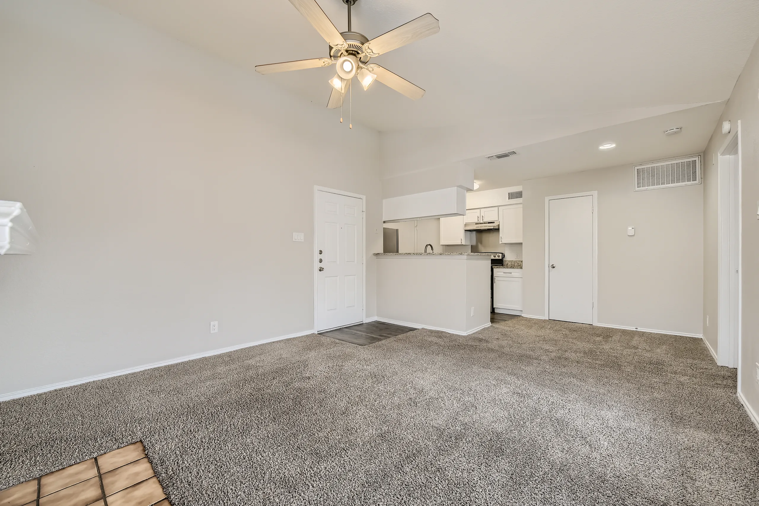 Open living room with plush carpet and view into renovated kitchen