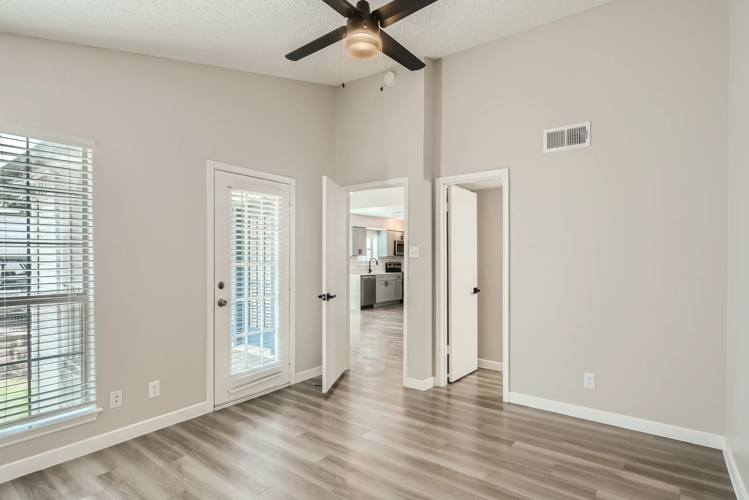 Primary bedroom with high ceilings, patio access, and kitchen view