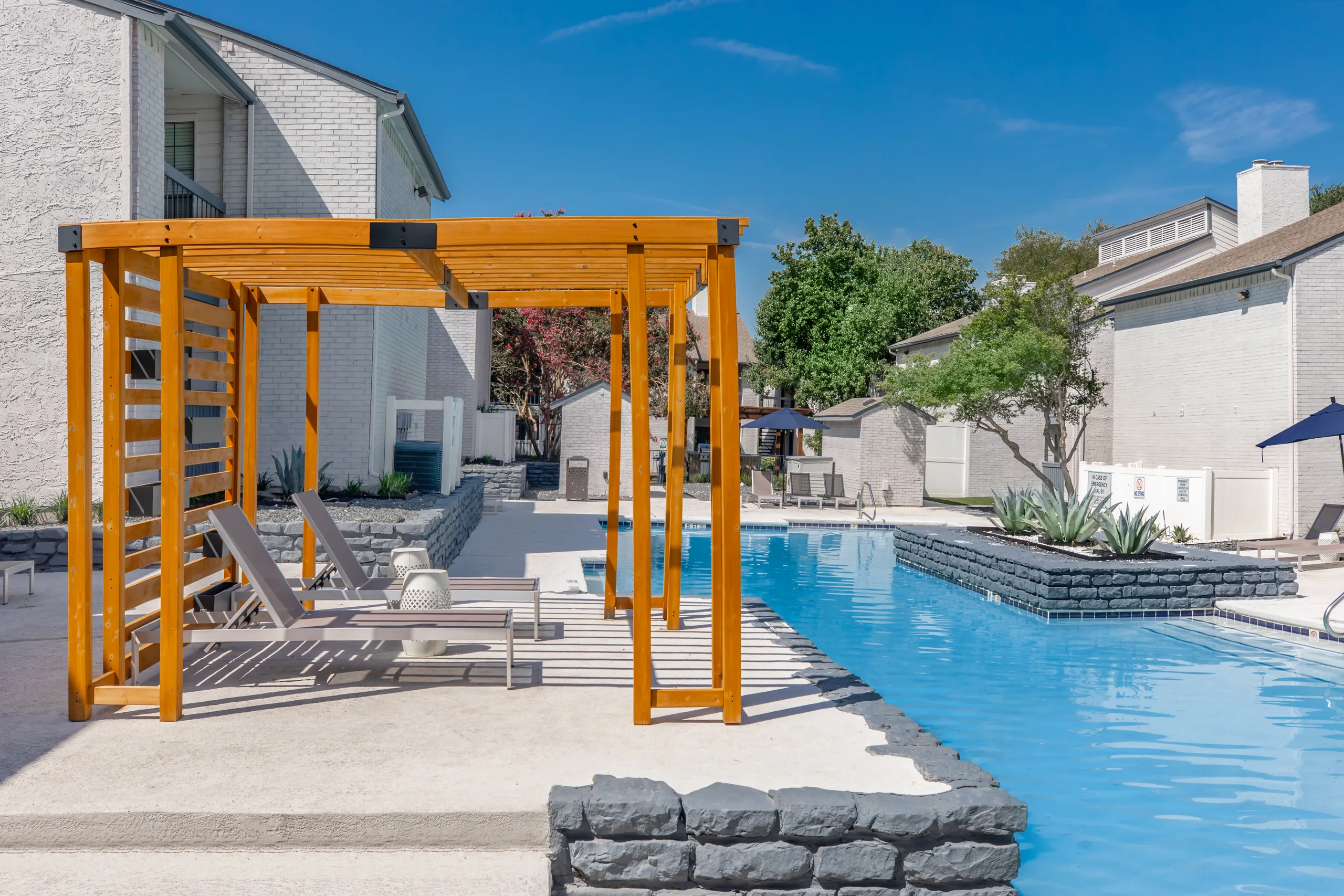 Wooden pergola with lounge seating alongside the community pool