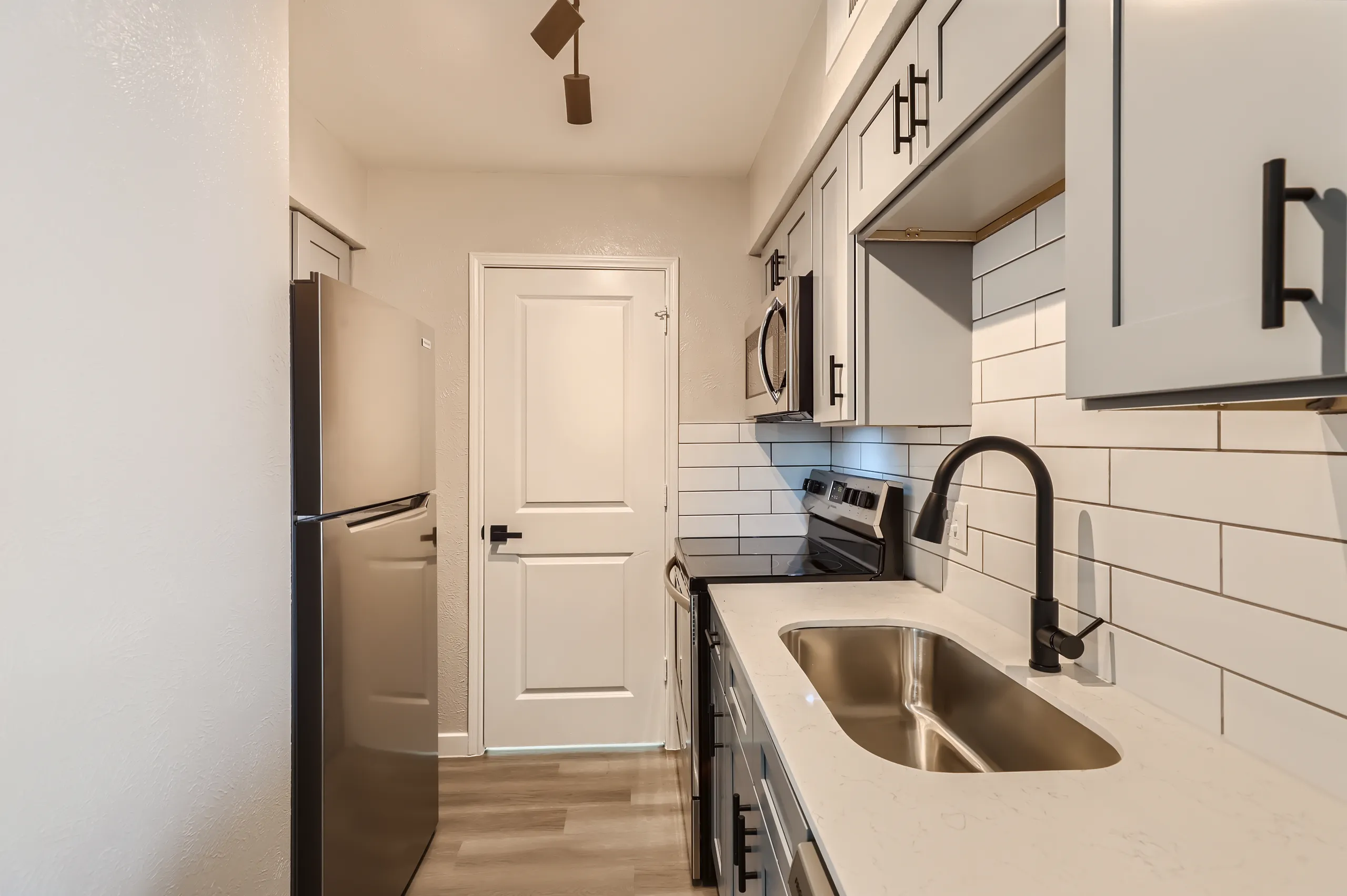 Galley kitchen with subway tile backsplash and stainless steel appliances