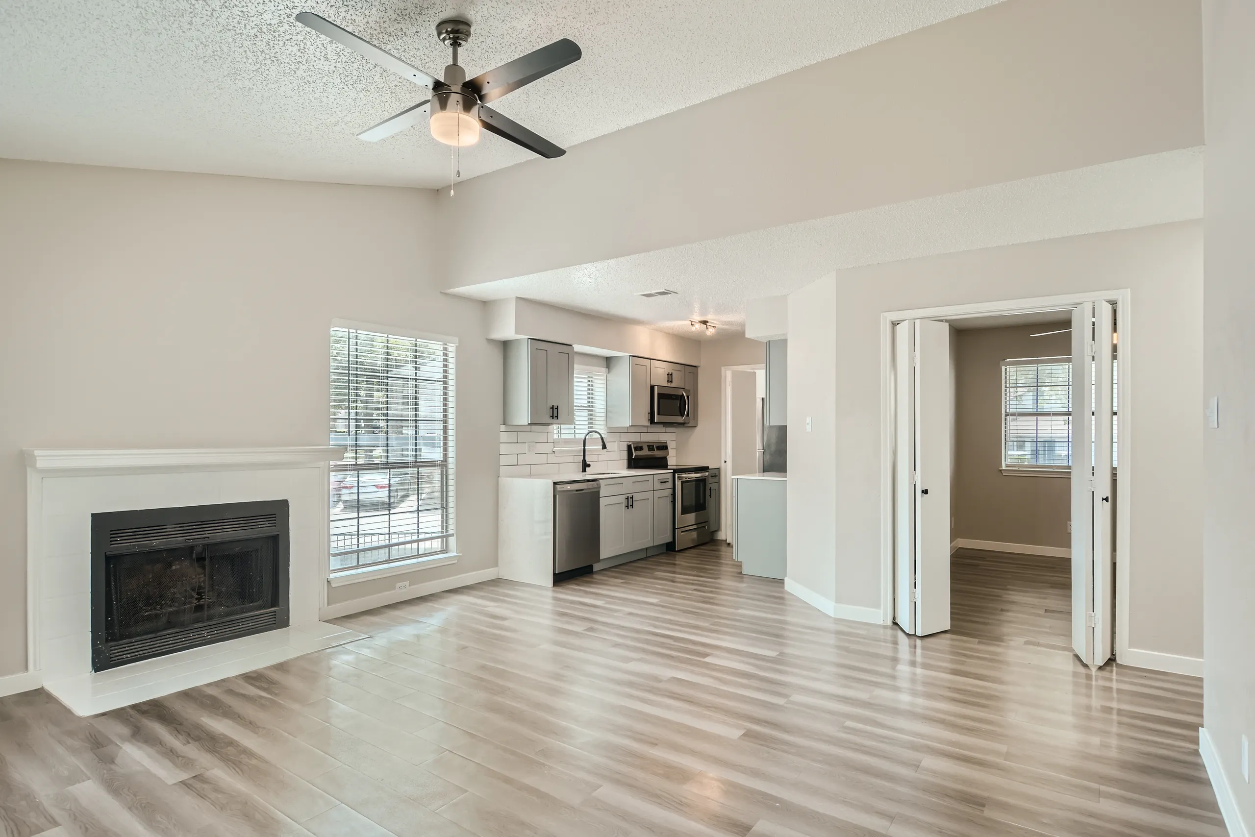 Open living room with tiled fireplace and view into renovated kitchen