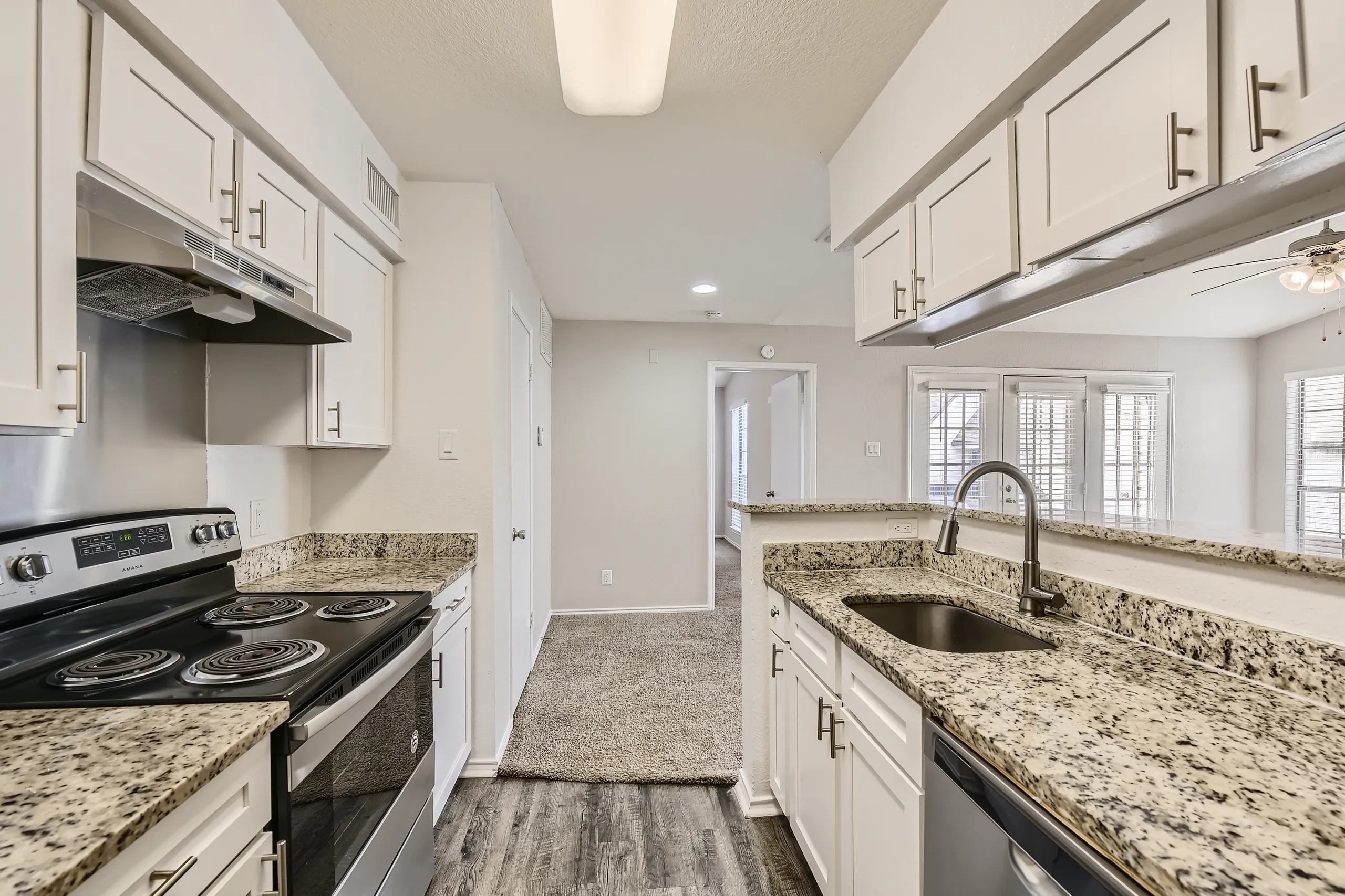 Renovated kitchen with granite countertops, white cabinetry, and stainless appliances