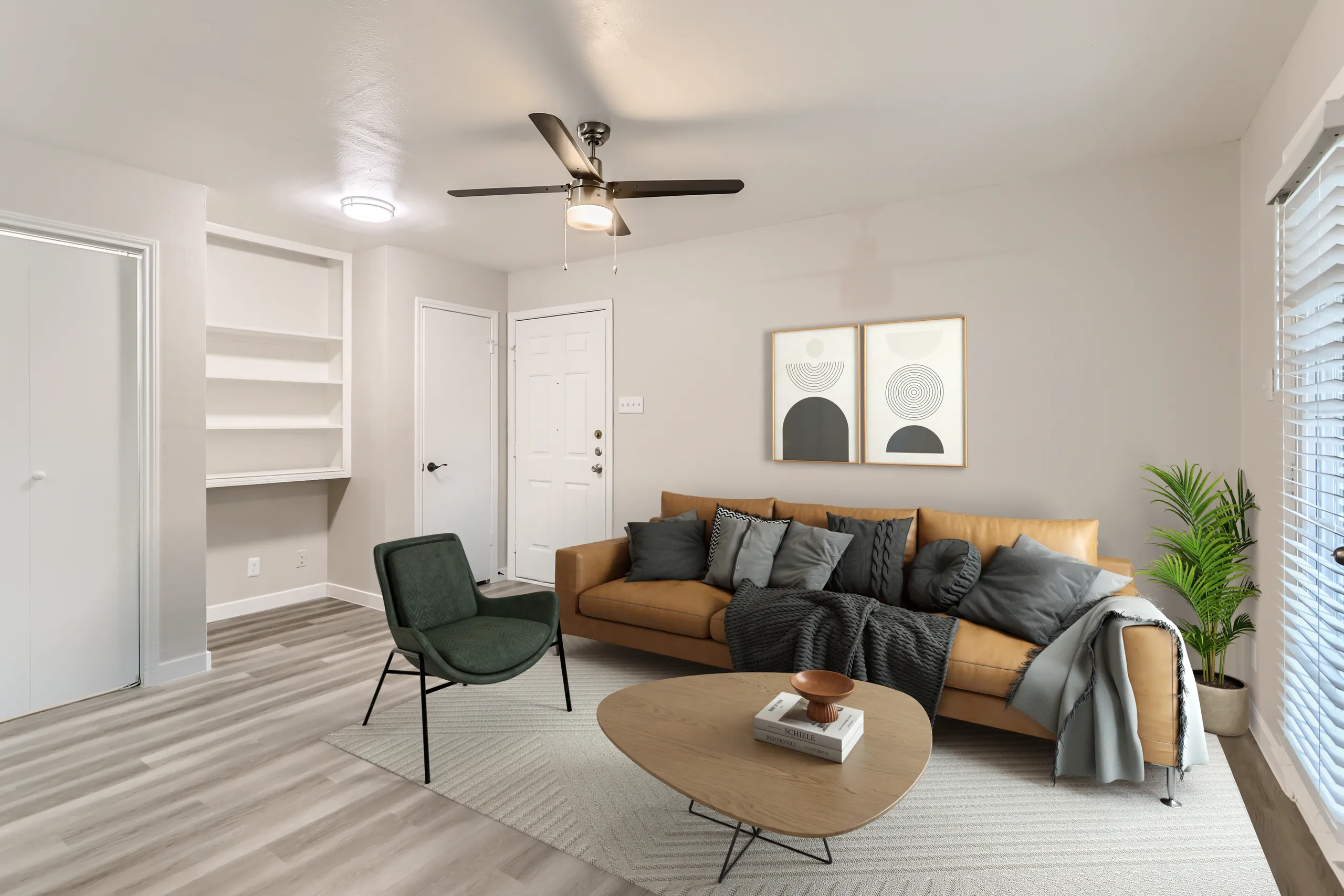 Modern apartment living room with leather sofa, built-in shelving, and ceiling fan