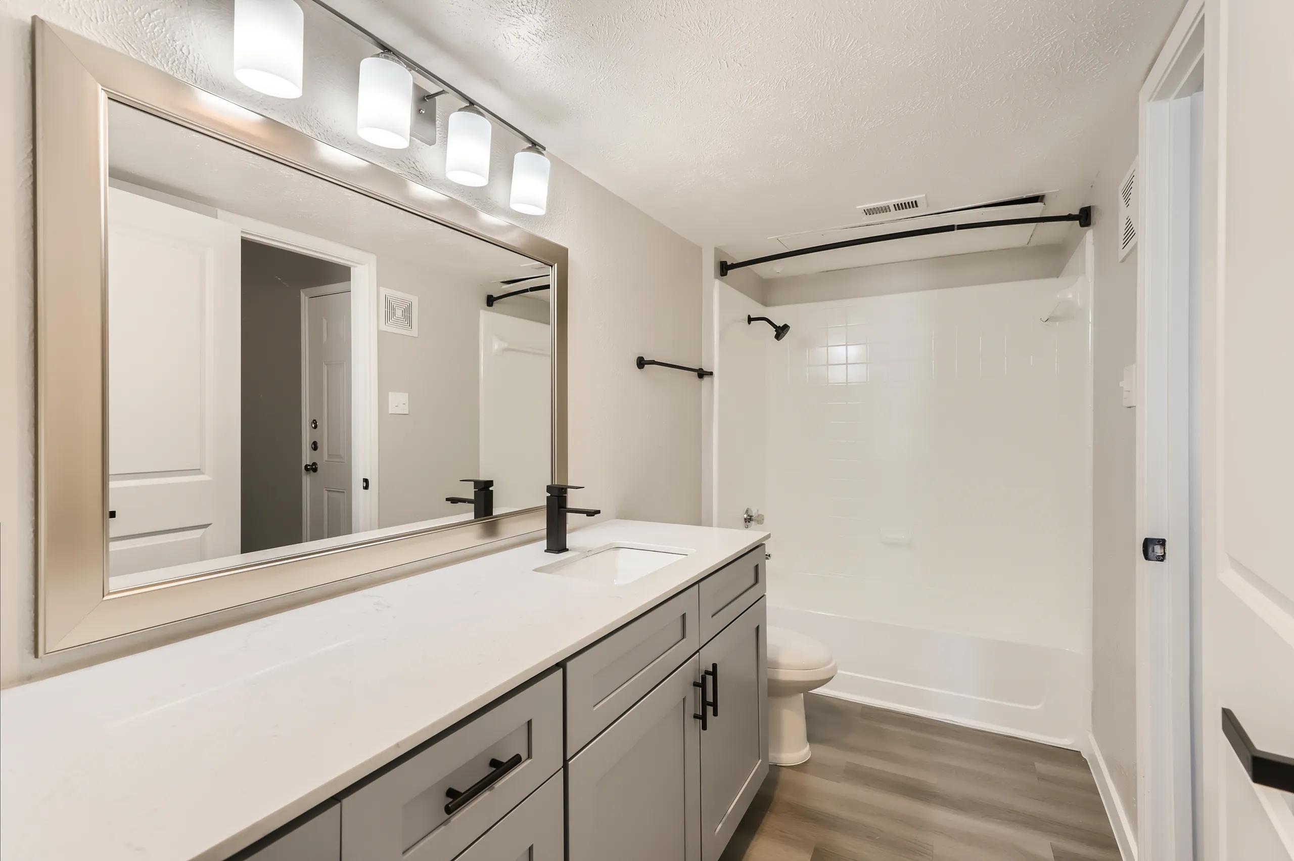 Bathroom with gray vanity, quartz counter, and tub-shower combo