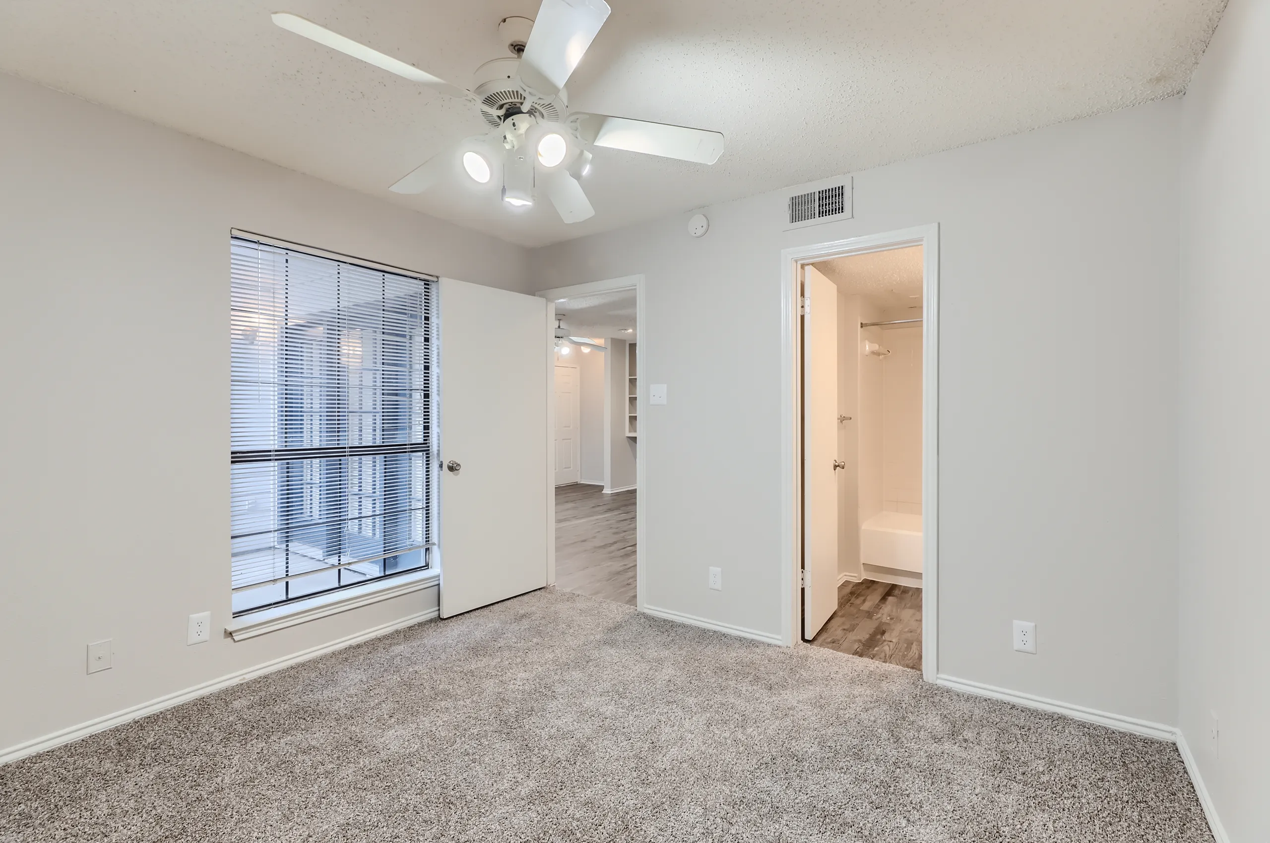 Primary bedroom with carpet, ceiling fan, and en-suite bathroom access