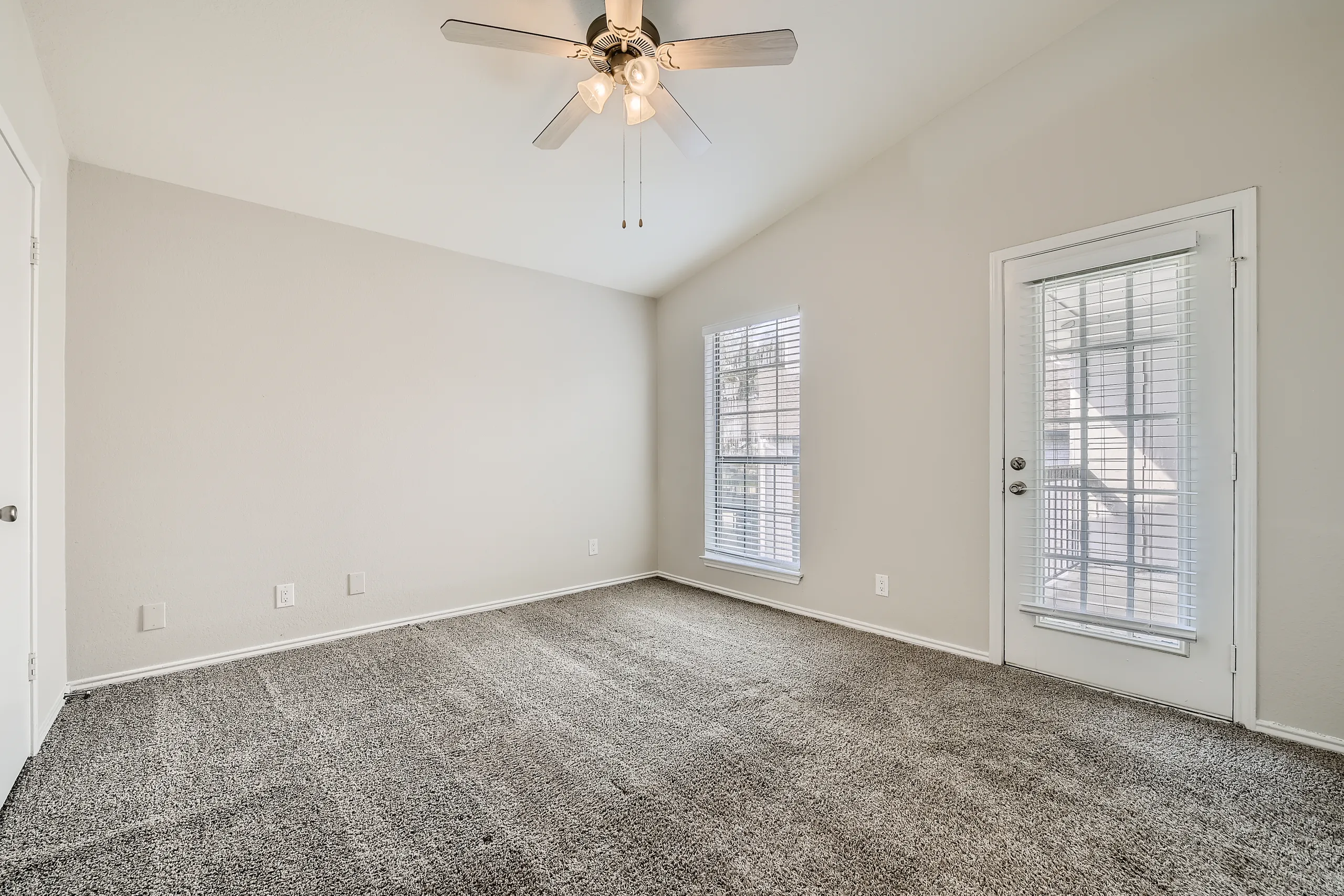 Primary bedroom with plush carpet, ceiling fan, and private patio door