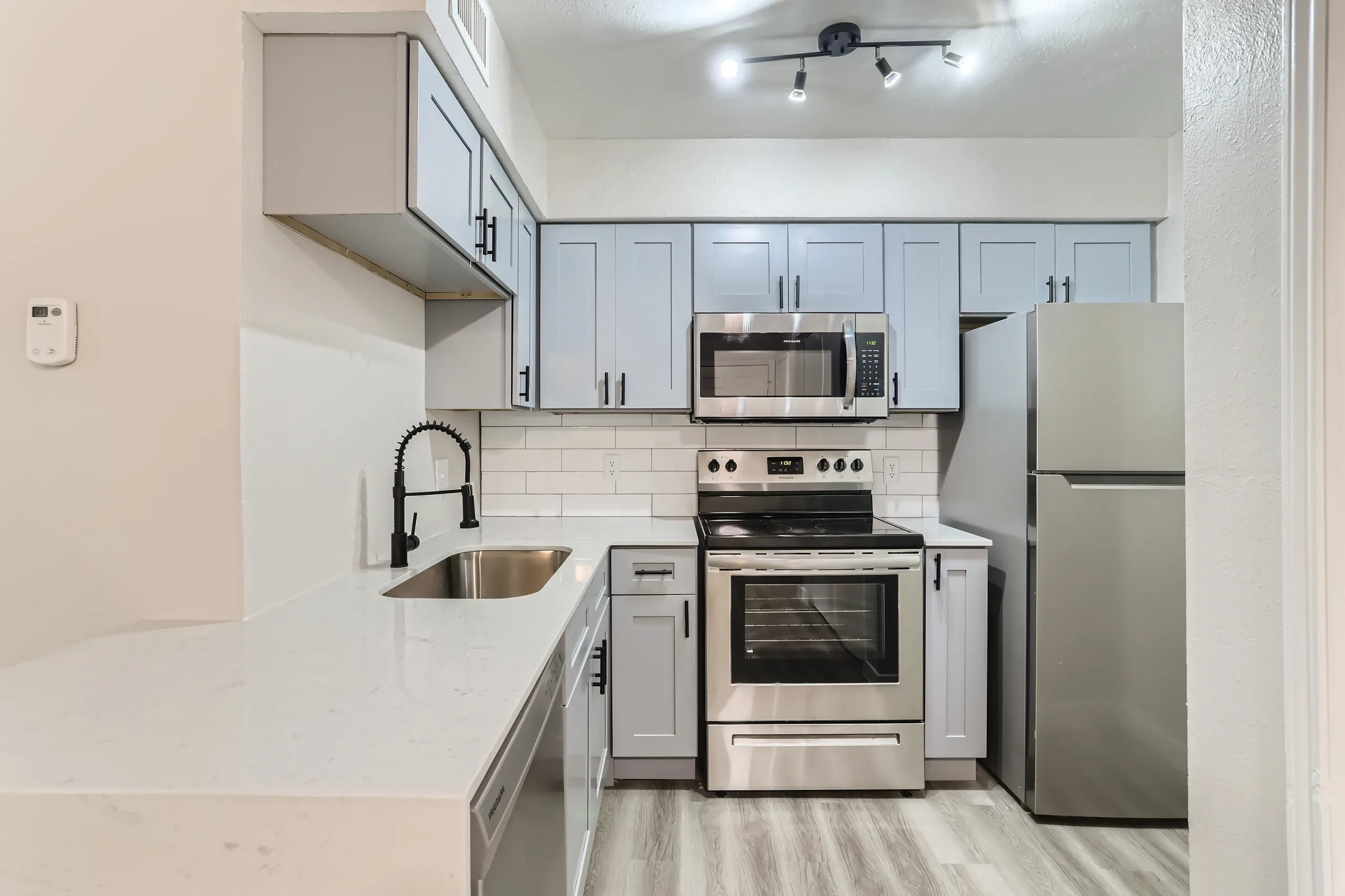 Renovated kitchen with stainless steel appliances, quartz countertops, and subway tile backsplash