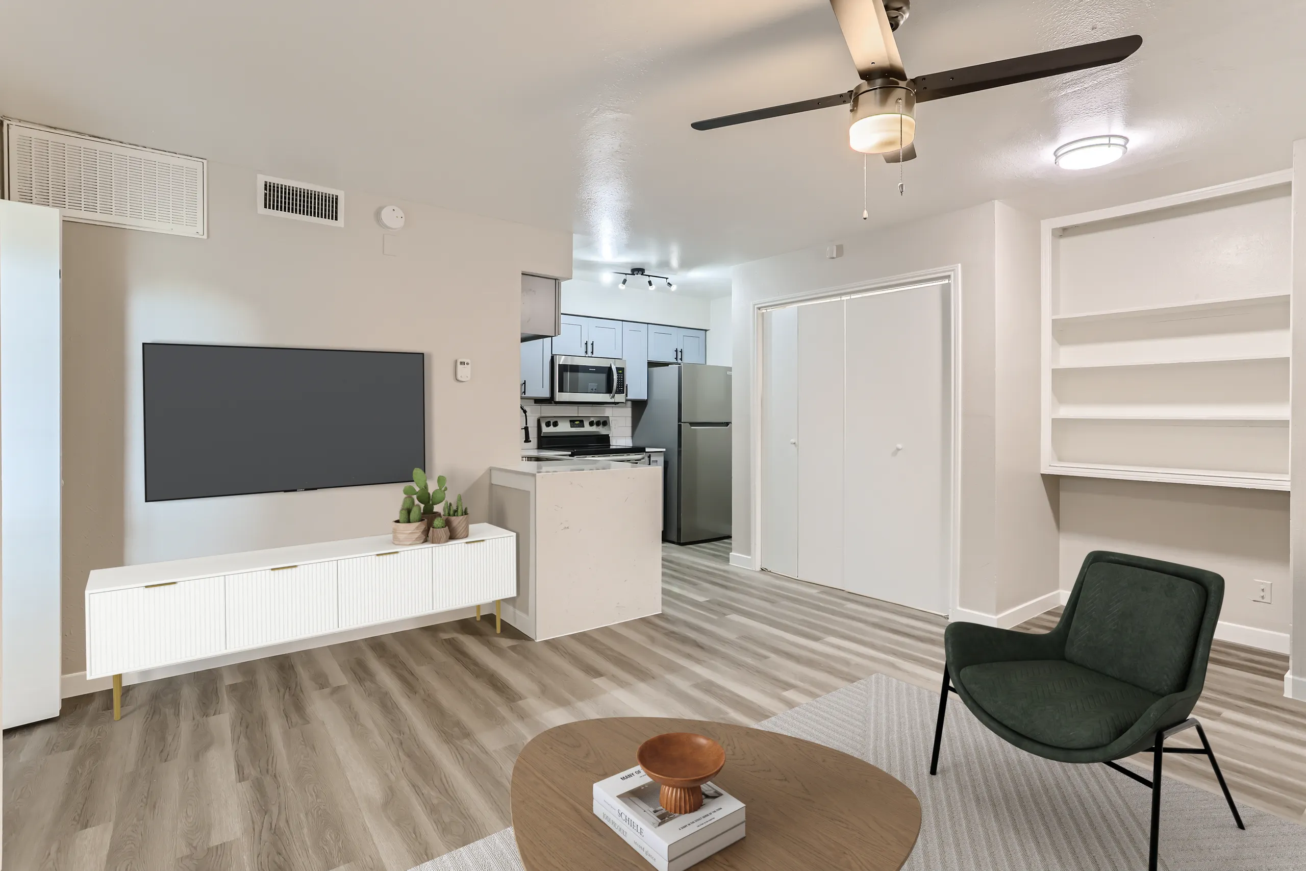 Renovated apartment living room with wood-look flooring, wall-mounted TV, and open kitchen view