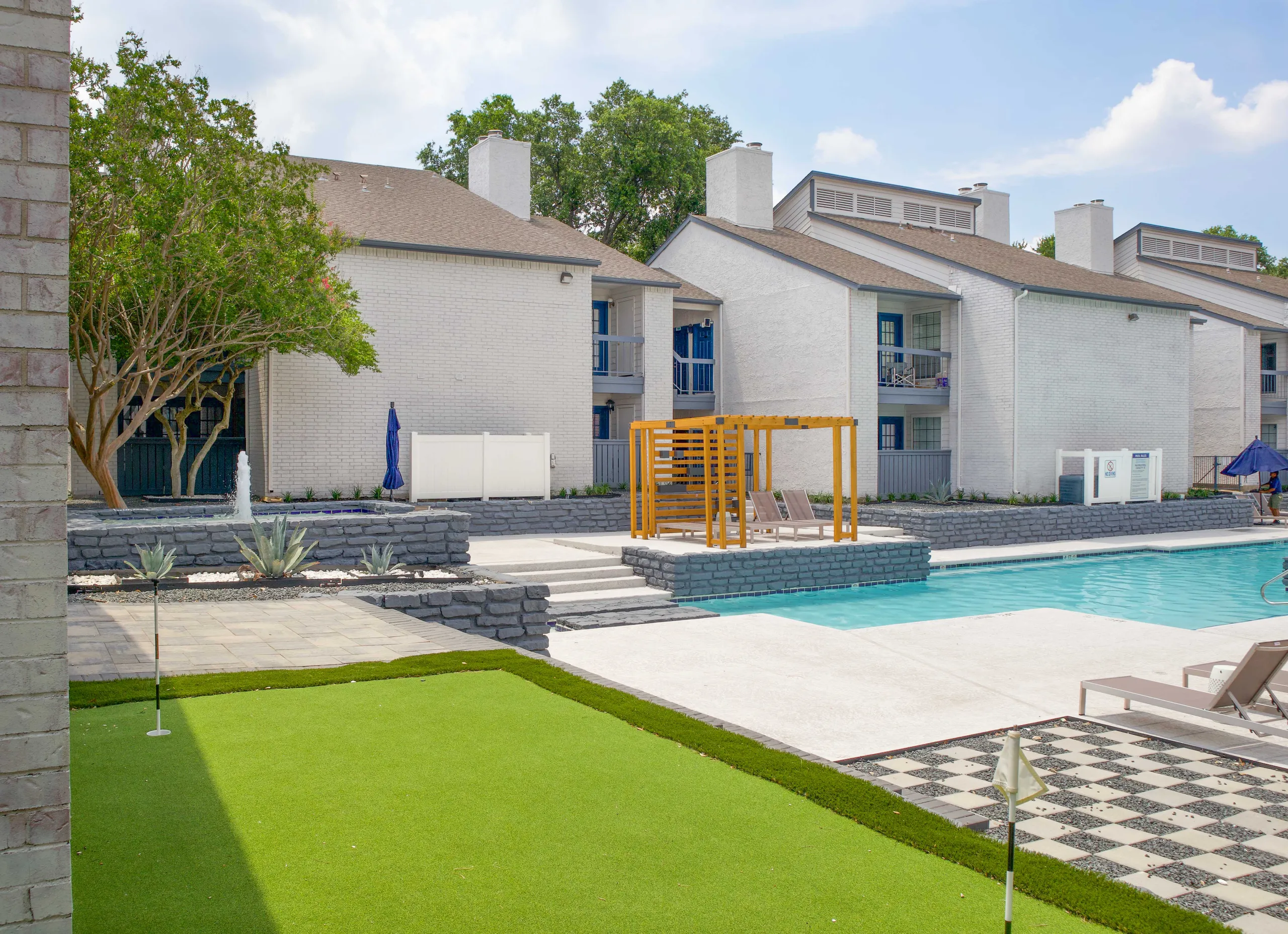 Putting green and pool deck with pergola seating at Rise Highland Meadows