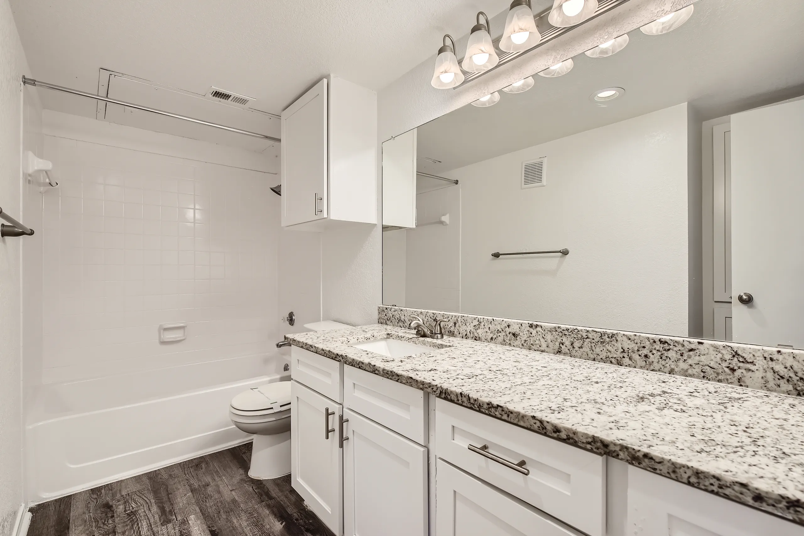 Renovated bathroom with granite vanity and tub-shower combo