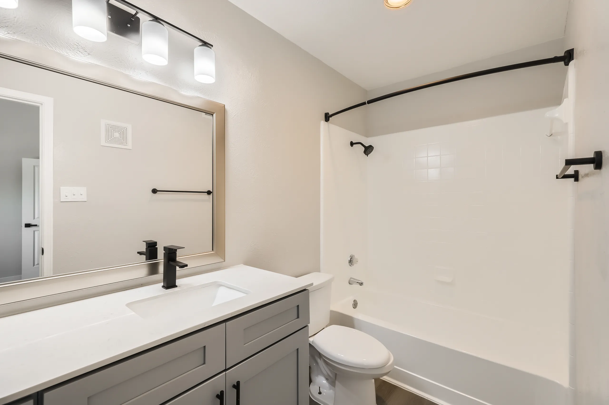 Primary bathroom with gray vanity and matte black fixtures