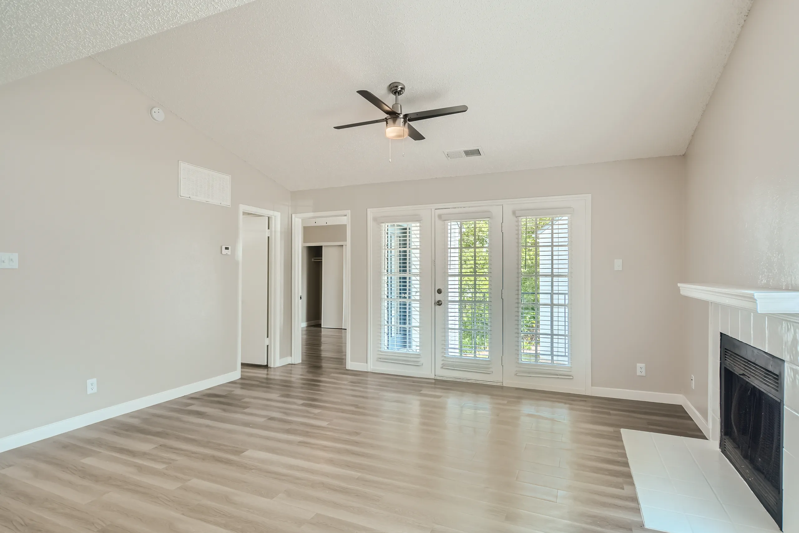 Living room with wood-look flooring, tiled fireplace, and French door access