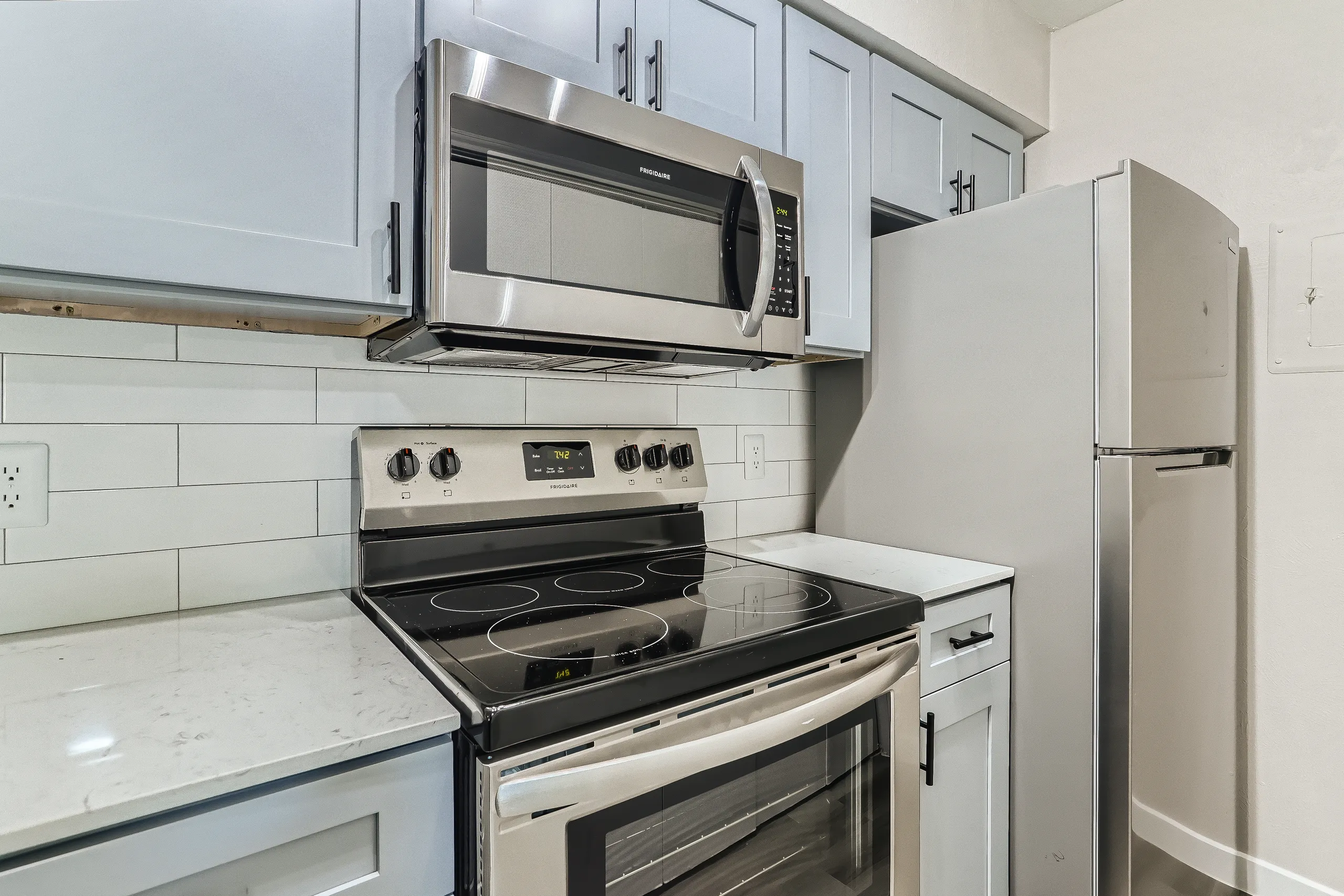 Renovated kitchen with stainless steel Frigidaire appliances and subway tile backsplash