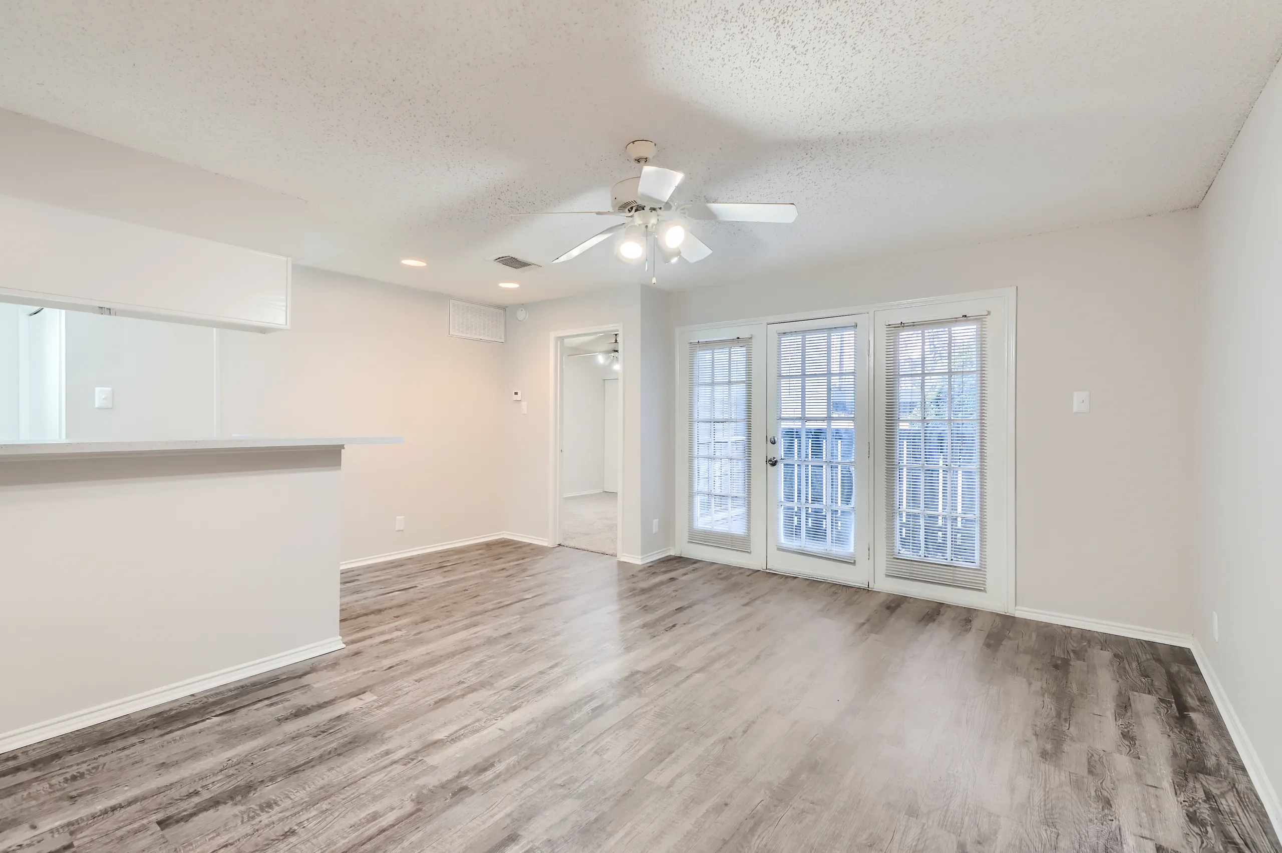 Living room with wood-look flooring and French doors leading to a private balcony