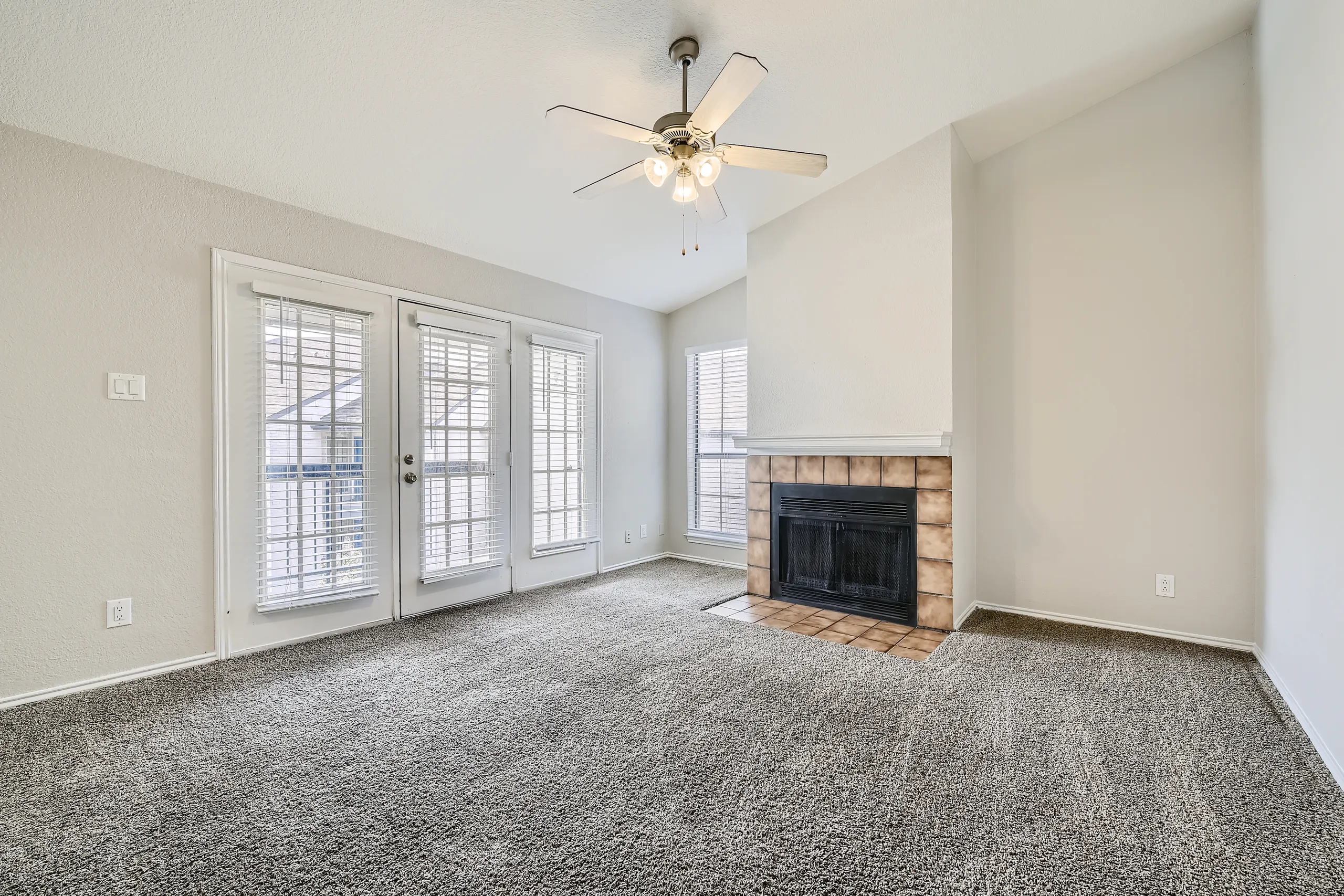 Living room with tiled fireplace, plush carpet, and French door access