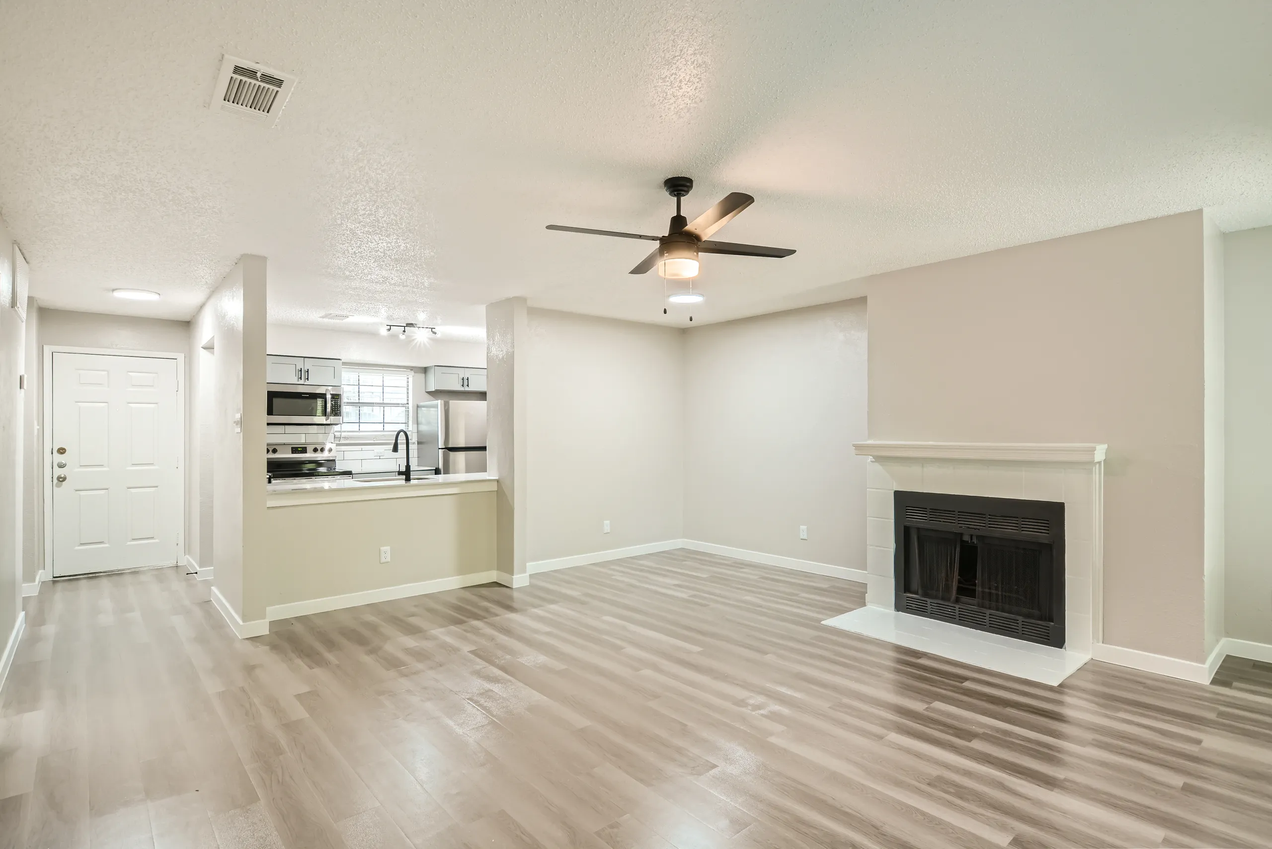 Open living room with tiled fireplace and kitchen view