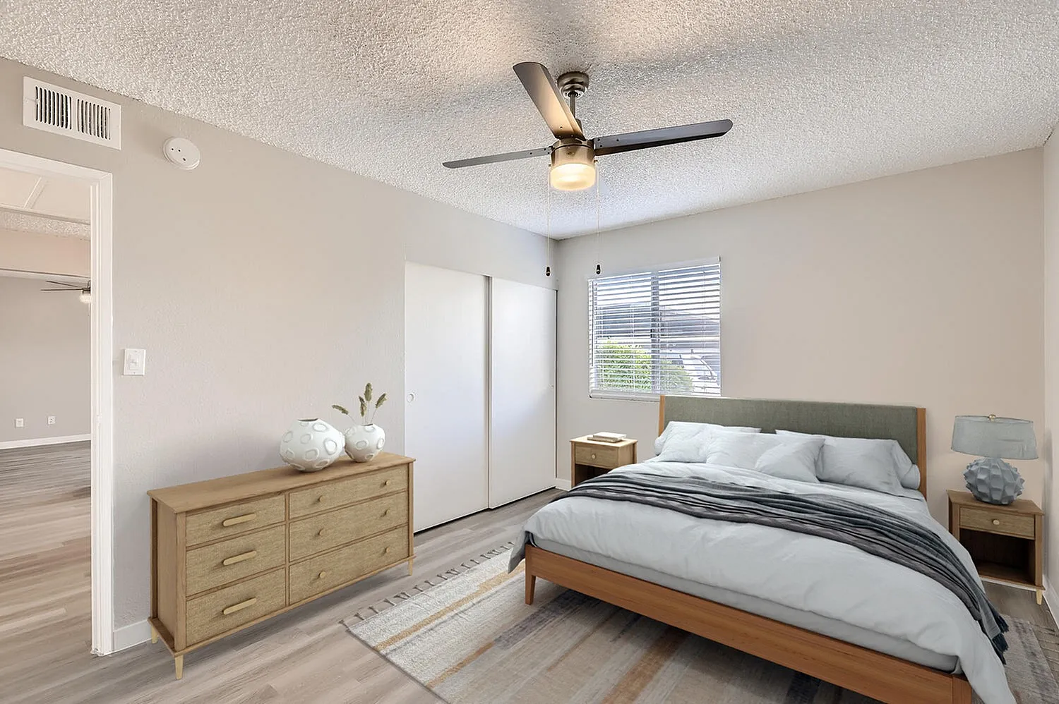 Primary bedroom, wood-style plank flooring, ceiling fan with light, wood dresser