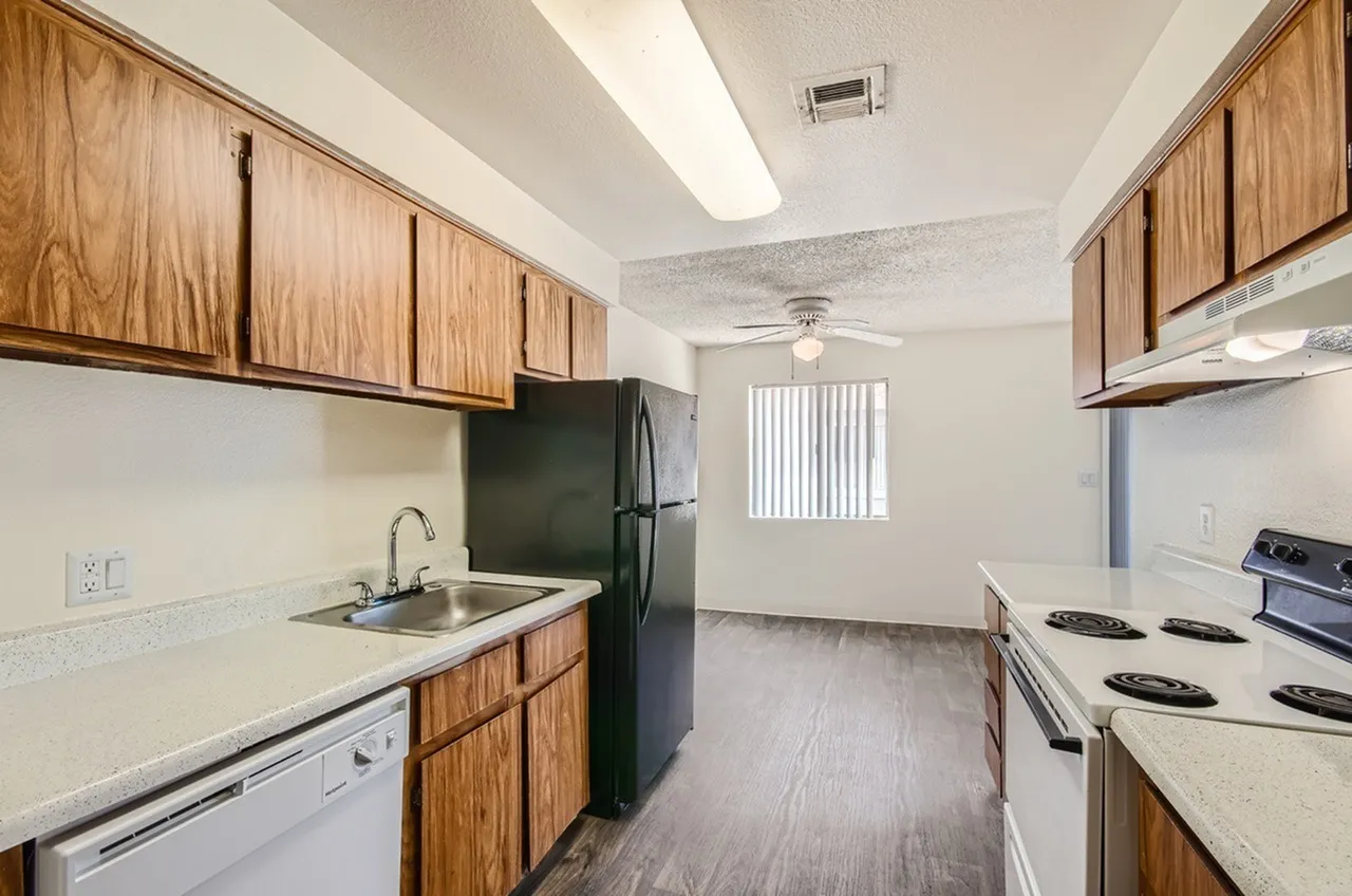 Kitchen, wood cabinetry, white countertops, black appliances, wood-style plank flooring