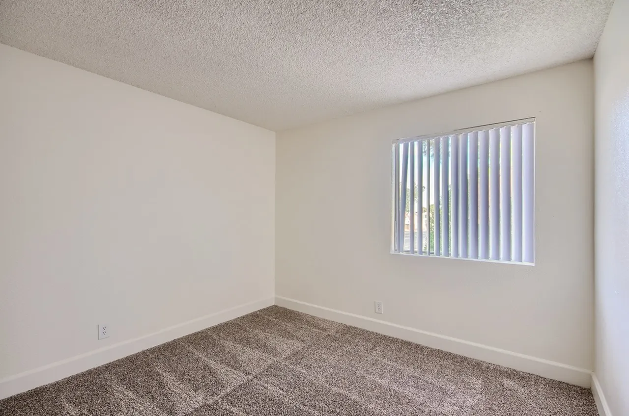 Bedroom, gray carpeted flooring, textured ceiling, vertical blinds window
