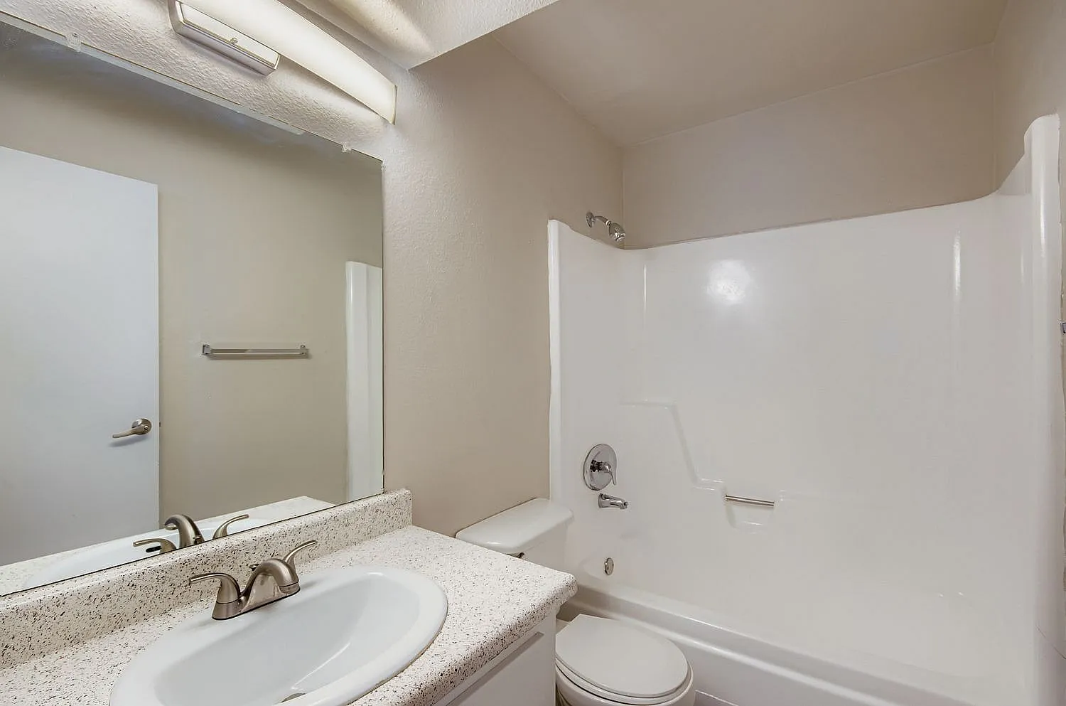 Bathroom, speckled quartz countertop, white vanity sink, white shower enclosure, toilet
