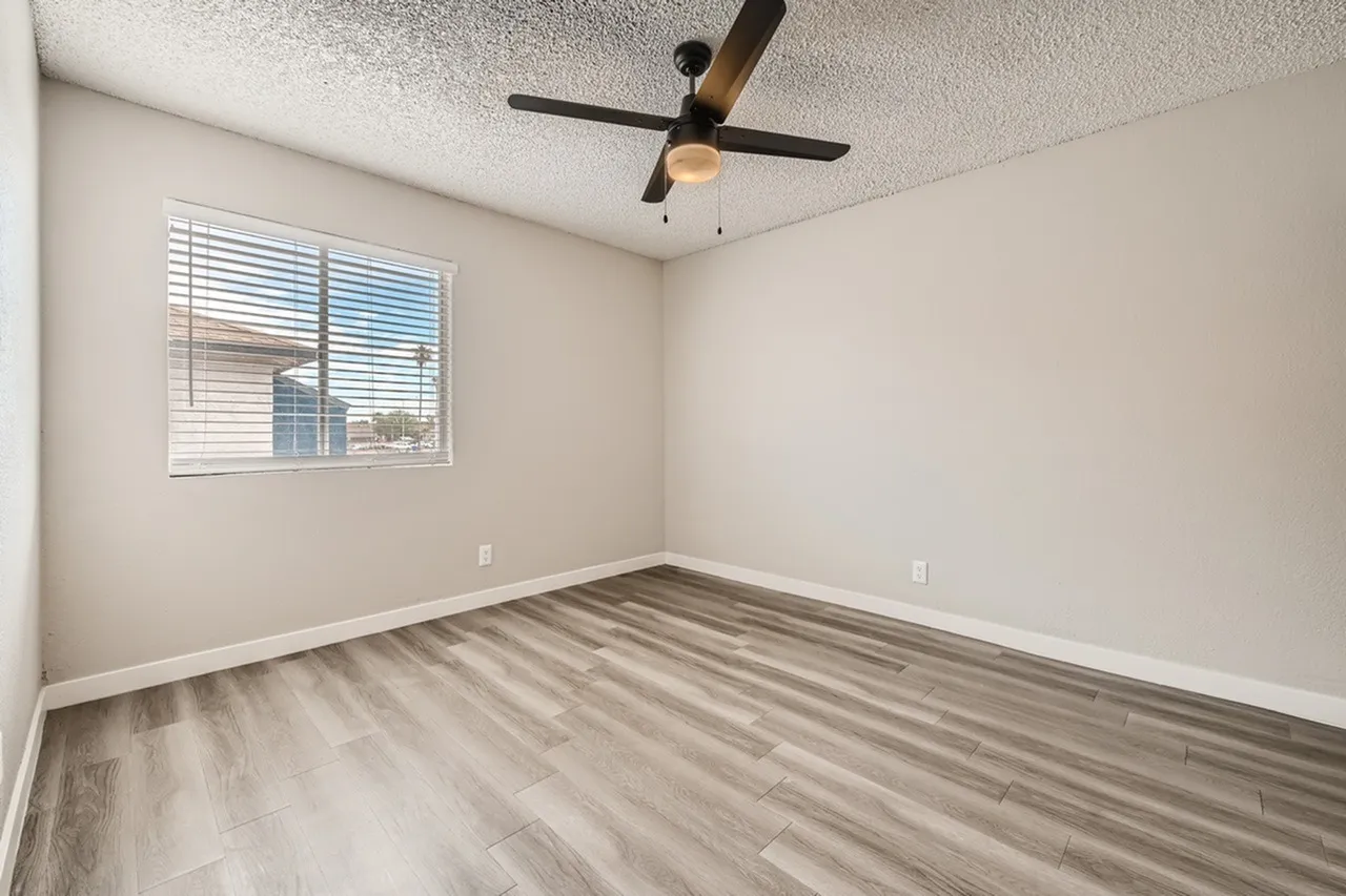 Bedroom, wood-style plank flooring, black ceiling fan, window with blinds