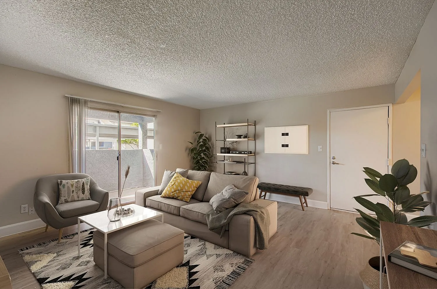 Living room with wood-style plank flooring, gray sofa, accent chair, area rug, potted plants, sliding patio doors