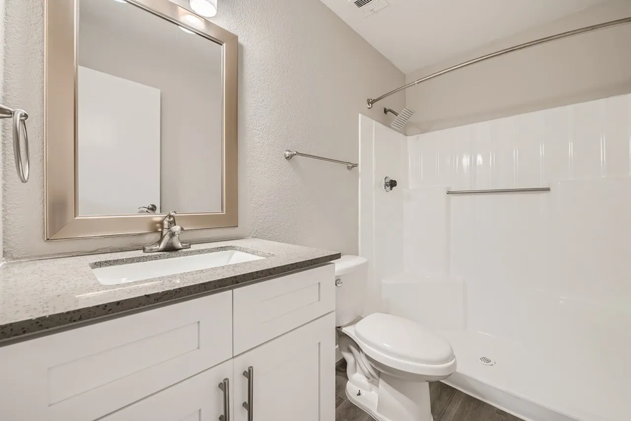 Bathroom, white shaker cabinetry, quartz countertops, framed mirror, glass shower enclosure