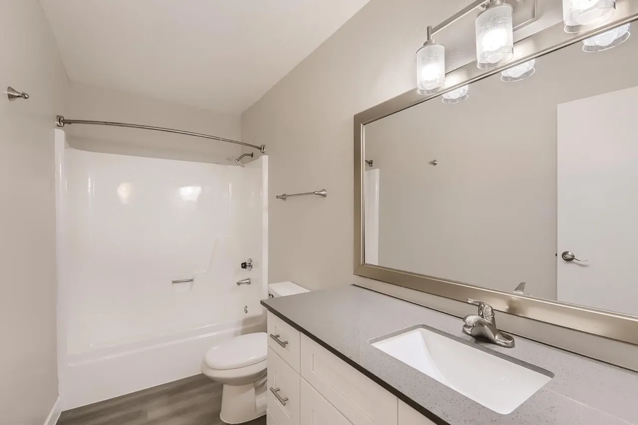 Primary bathroom, white vanity with undermount sink, quartz countertop, framed mirror, pendant lighting