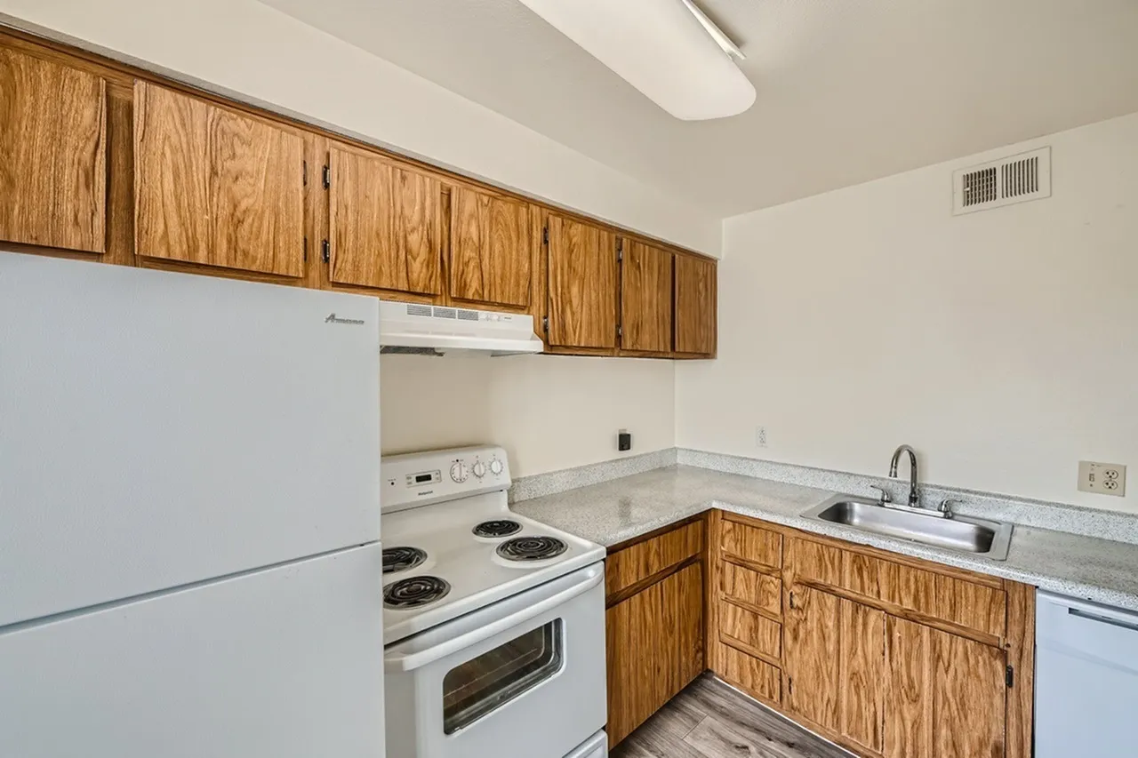 Kitchen, wood cabinetry, white appliances, laminate countertops, sink