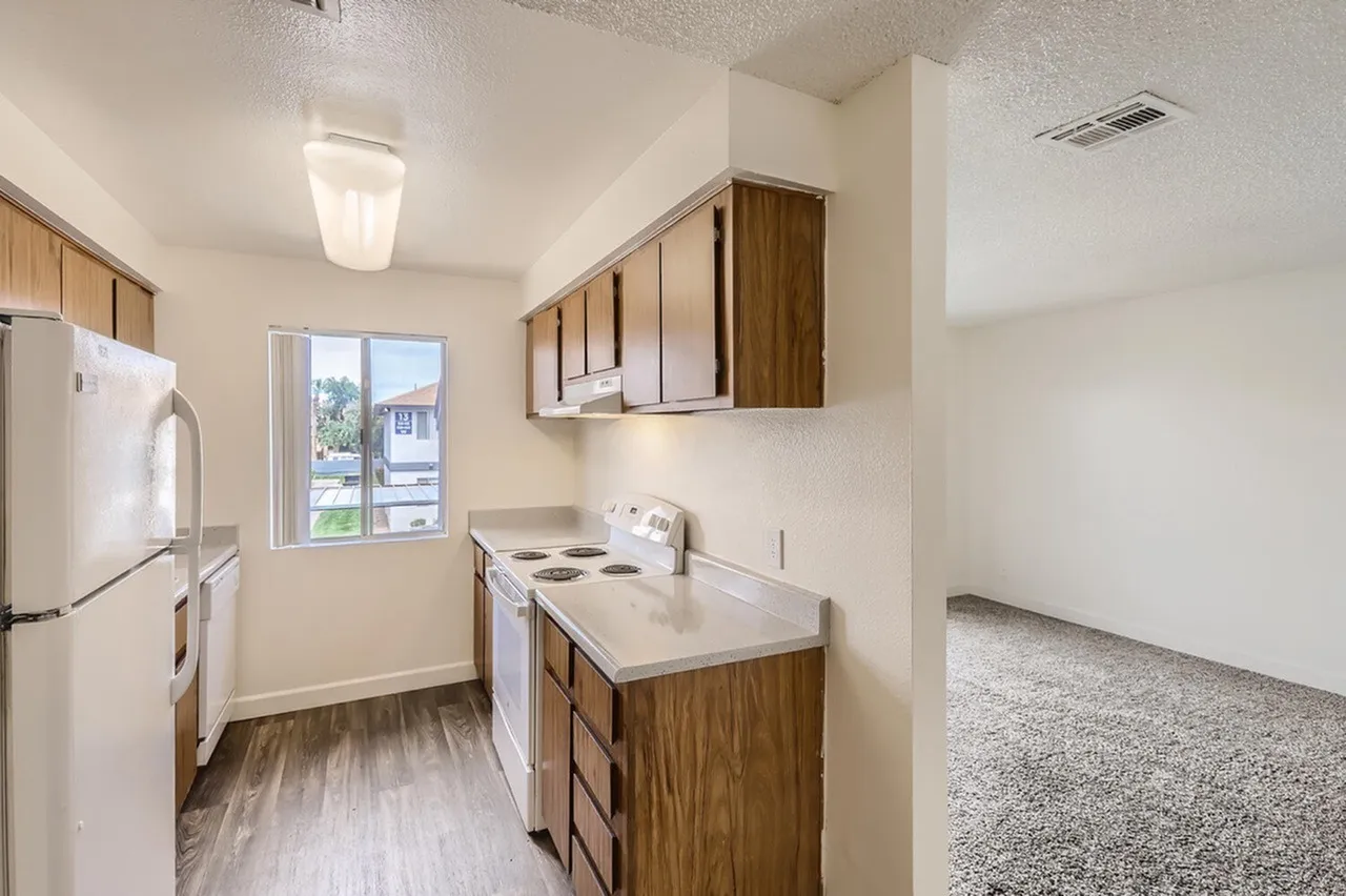 Kitchen with wood-style cabinetry, countertops, electric range, window, wood-style plank flooring
