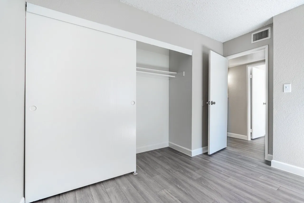 Bedroom, wood-style plank flooring, open closet with shelving, entry door