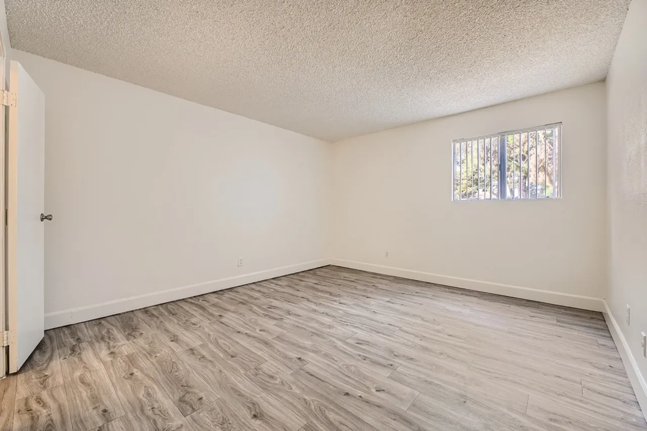 Bedroom, wood-style plank flooring, white walls, textured ceiling, large window