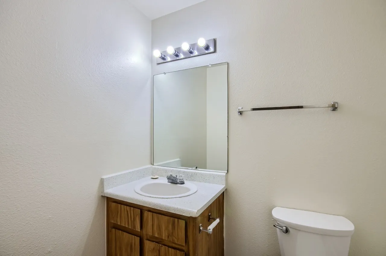 Bathroom, wood cabinetry vanity, white countertop, framed mirror, vanity lighting