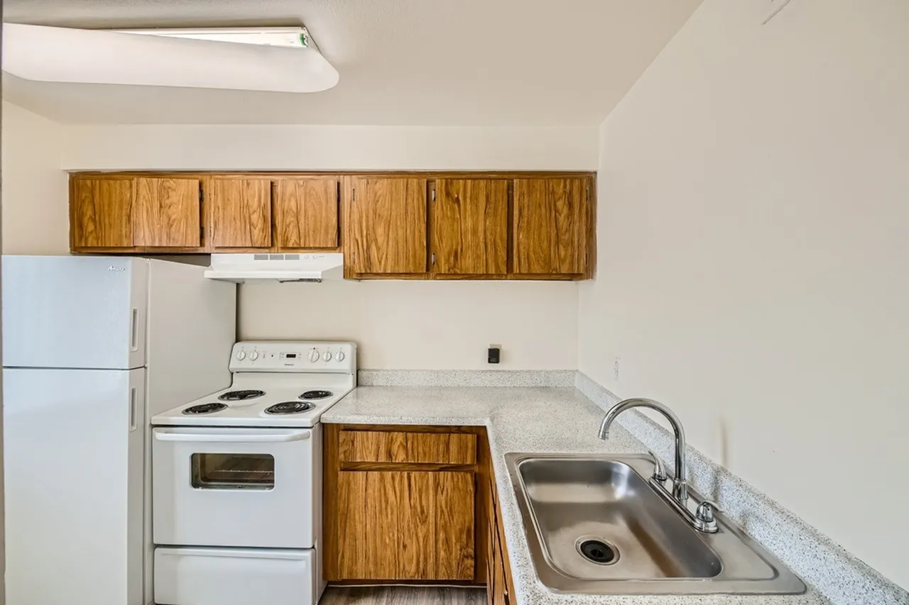 Kitchen, wood cabinetry, white electric range, stainless sink, quartz countertops