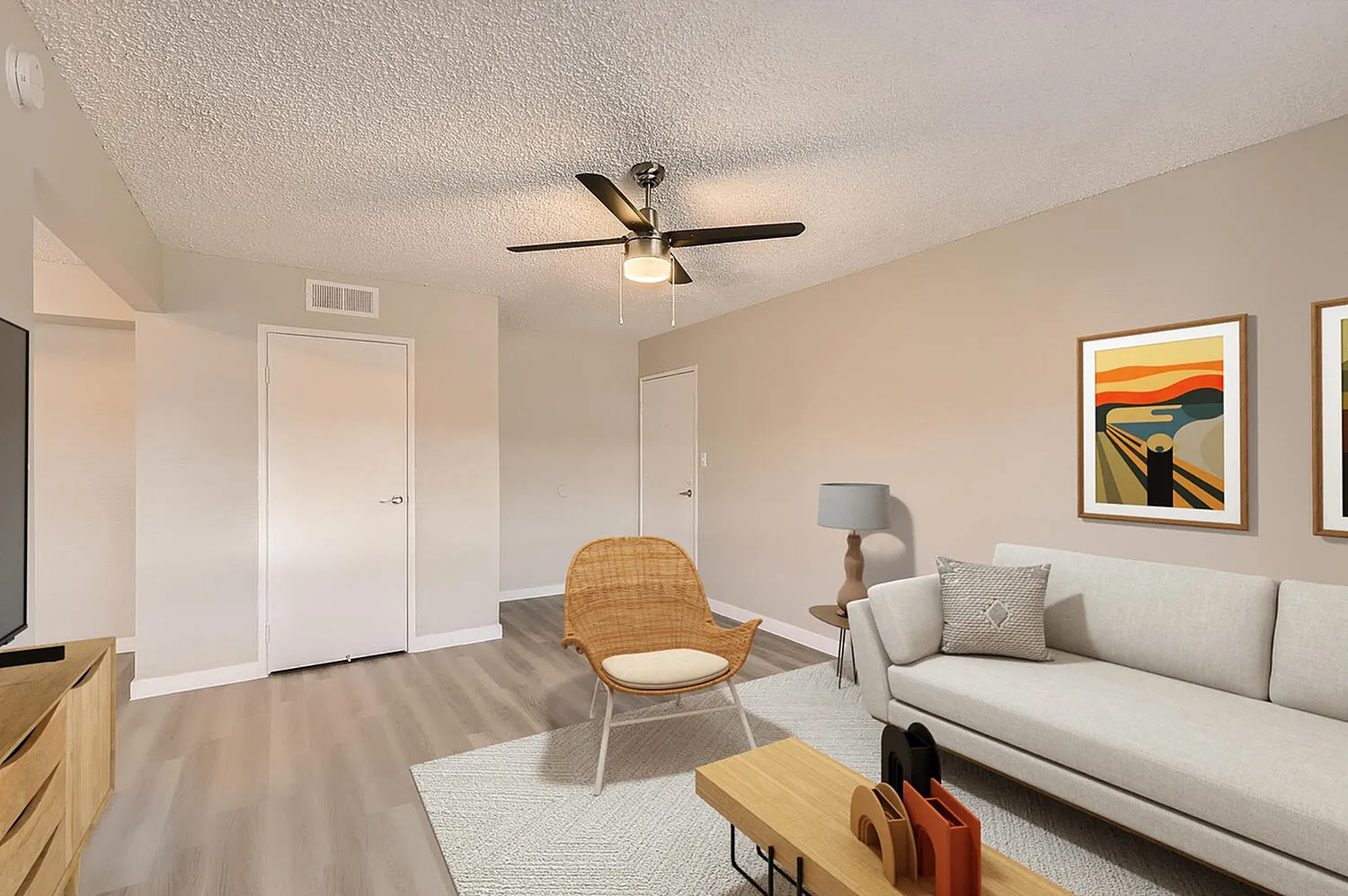 Living room, wood-style plank flooring, ceiling fan, white sofa, woven accent chair
