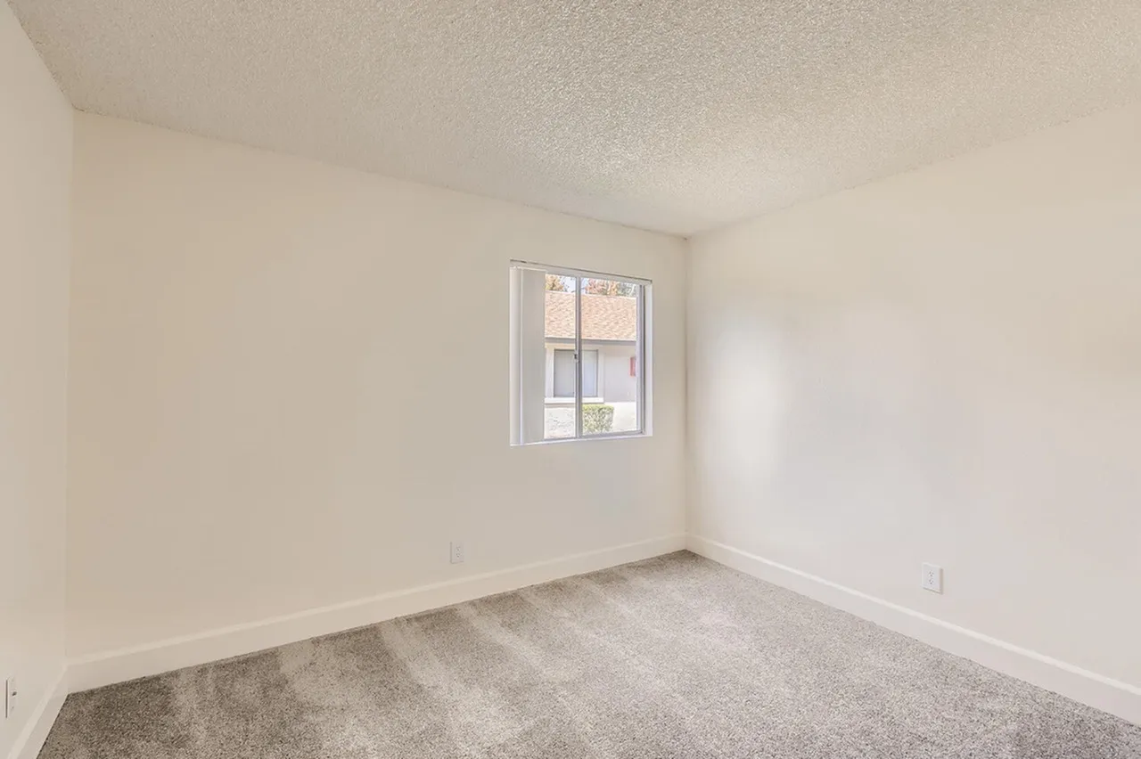 Bedroom, gray carpet flooring, window with natural light, white walls