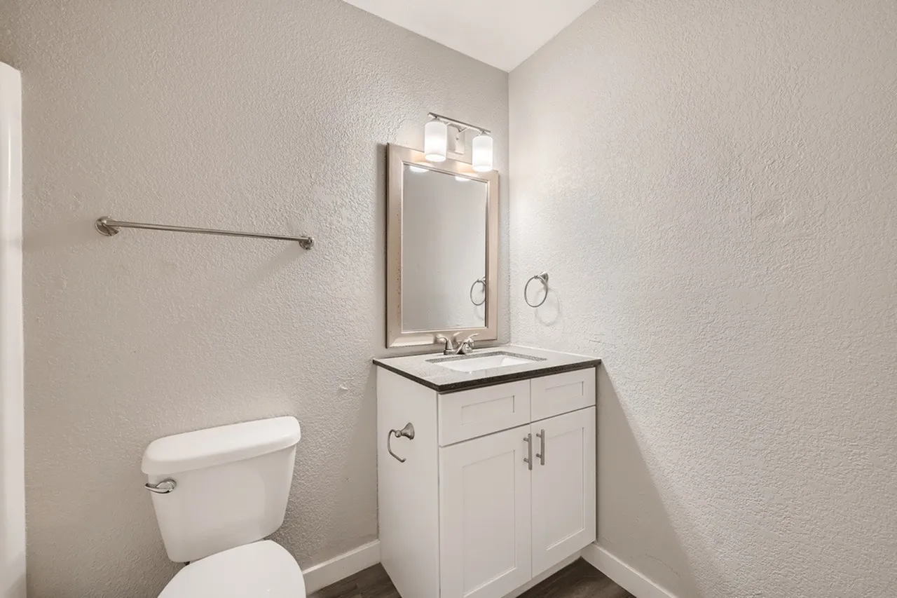 Bathroom, white cabinetry, black countertop, framed mirror with sconce lighting