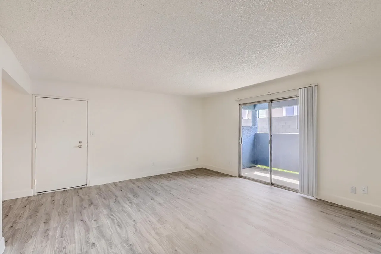 Living room, wood-style plank flooring, sliding glass door, white walls
